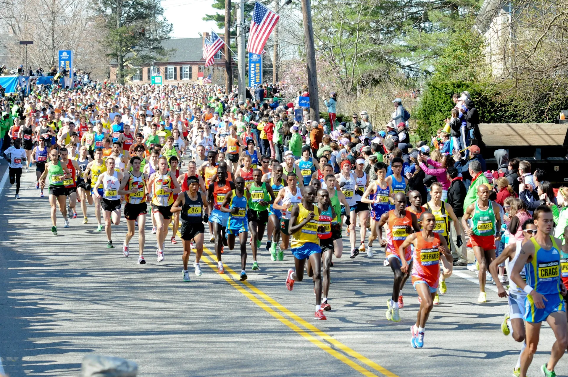 The image depicts a large group of marathon runners participating in a race. We see