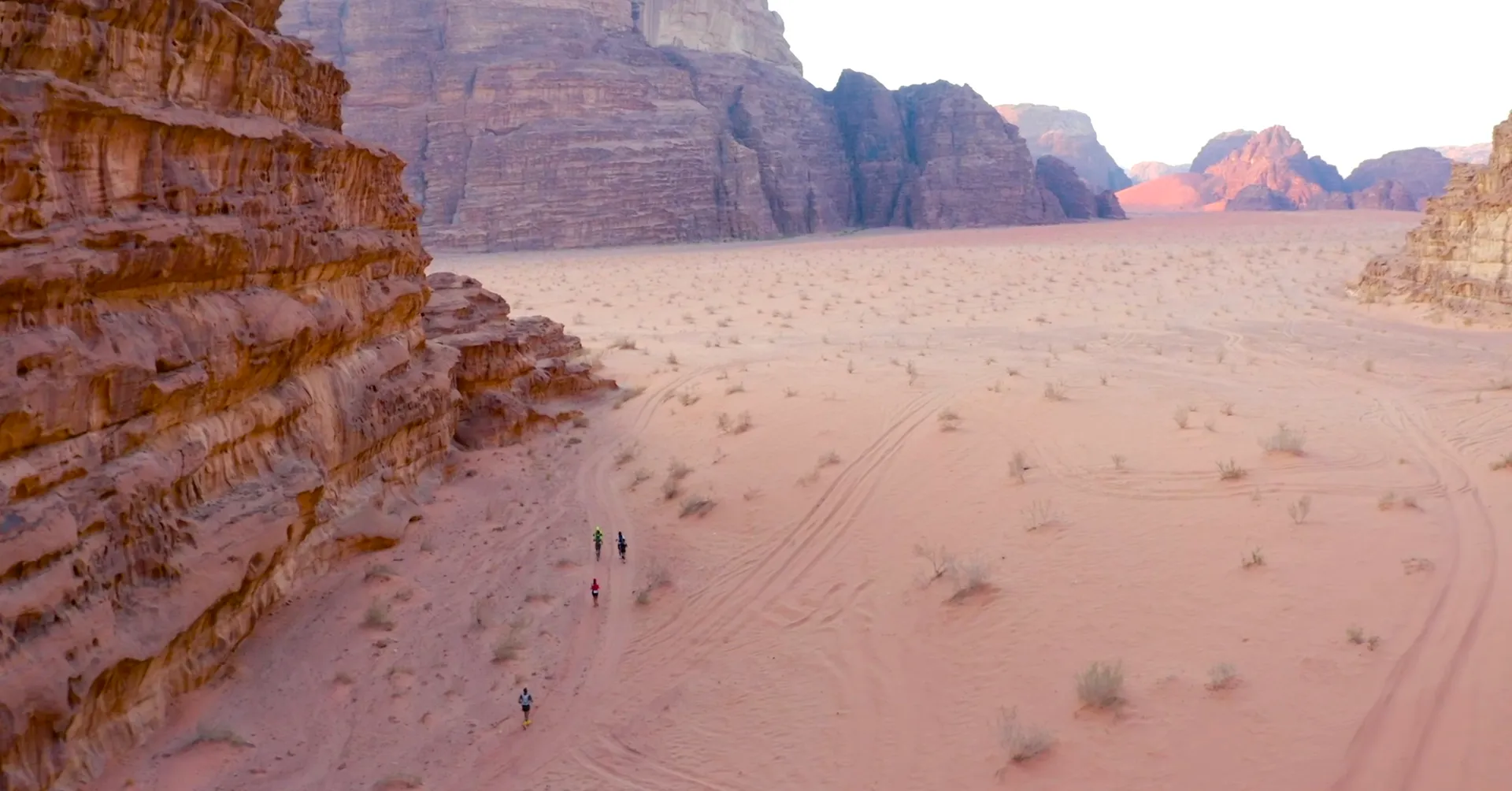 The image depicts a vast desert landscape with large rock formations or cliffs on the left