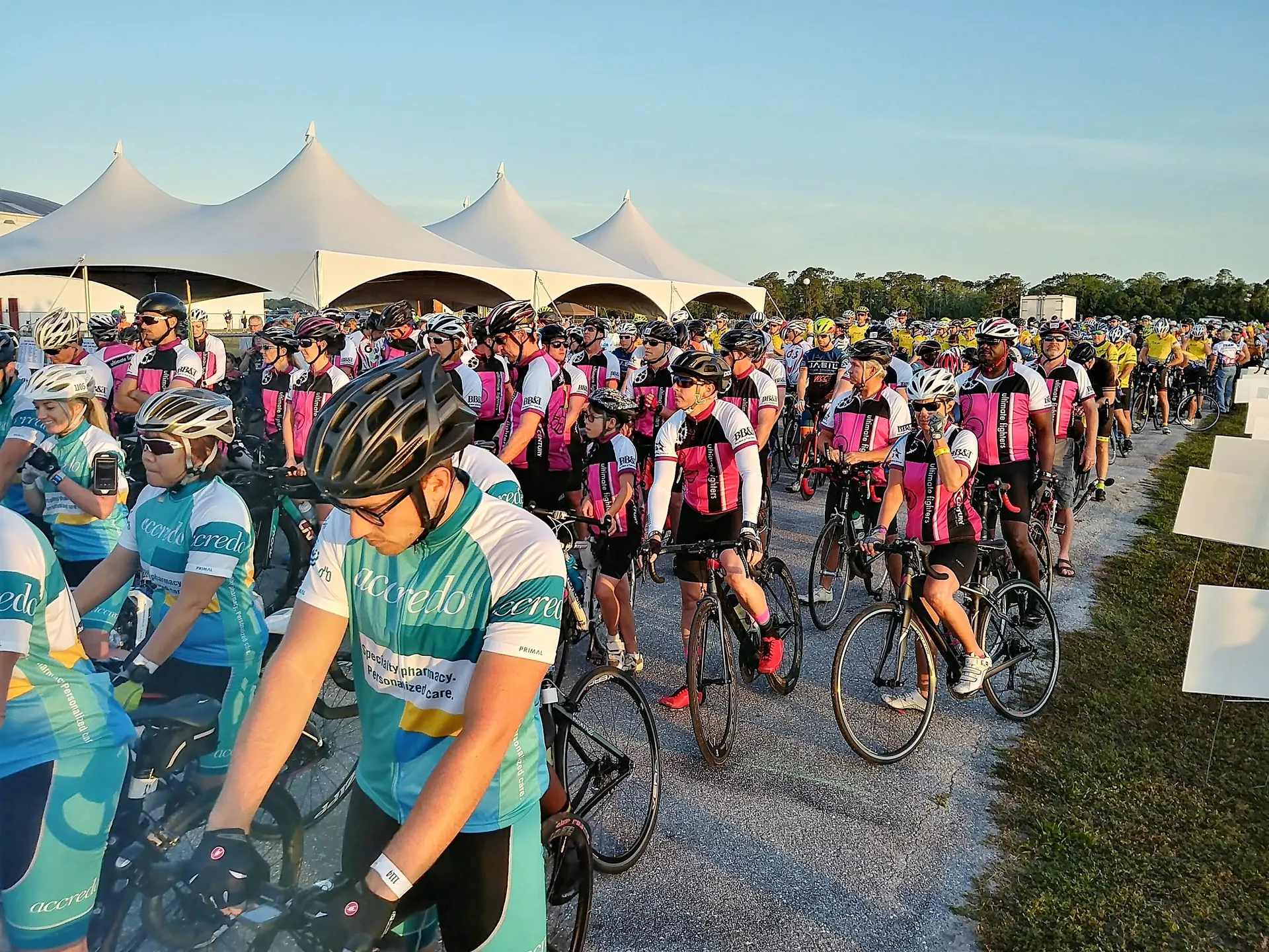 The image depicts a large group of cyclists gathered together for what appears to be a