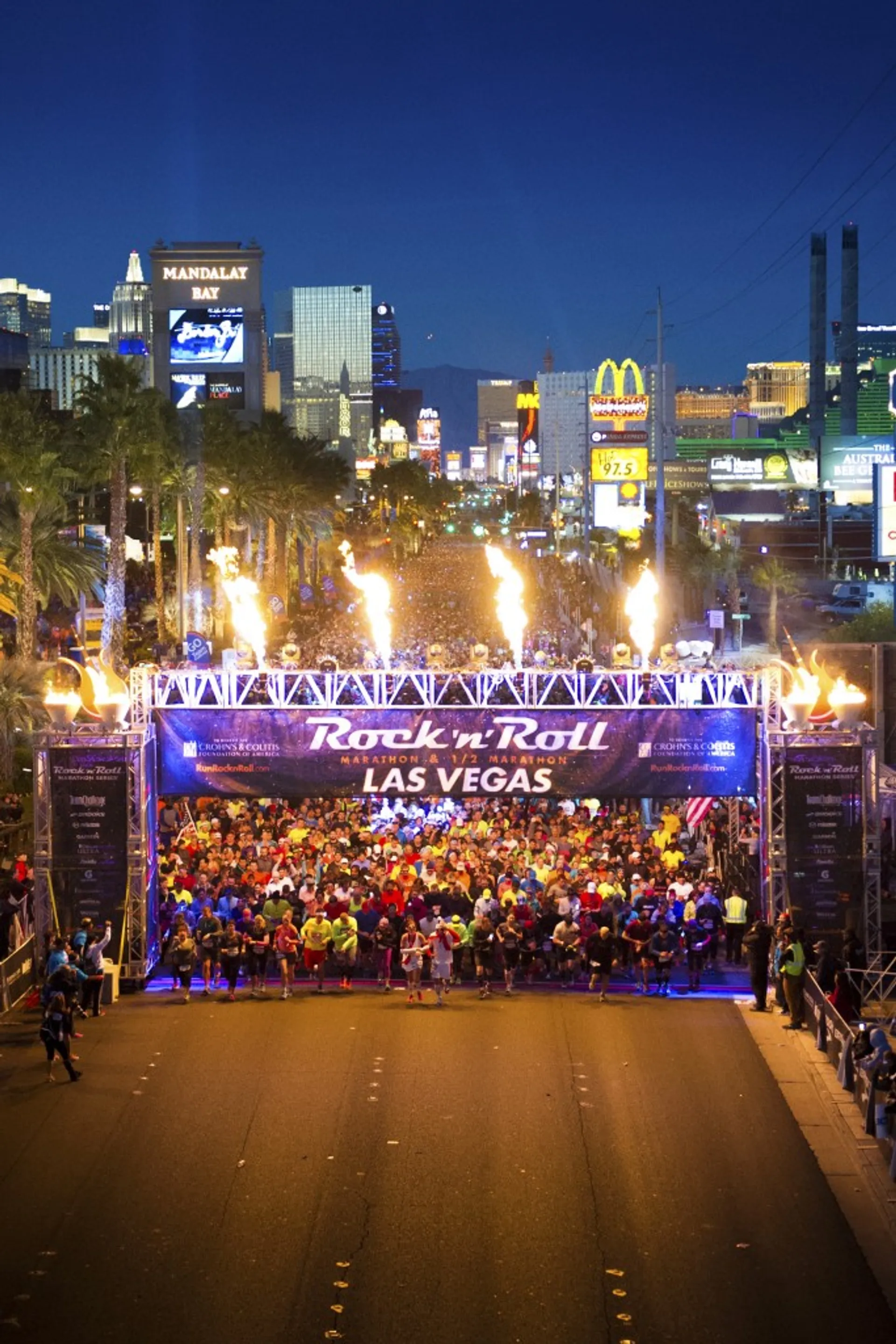 The image shows a large group of people gathered at the starting line of a night