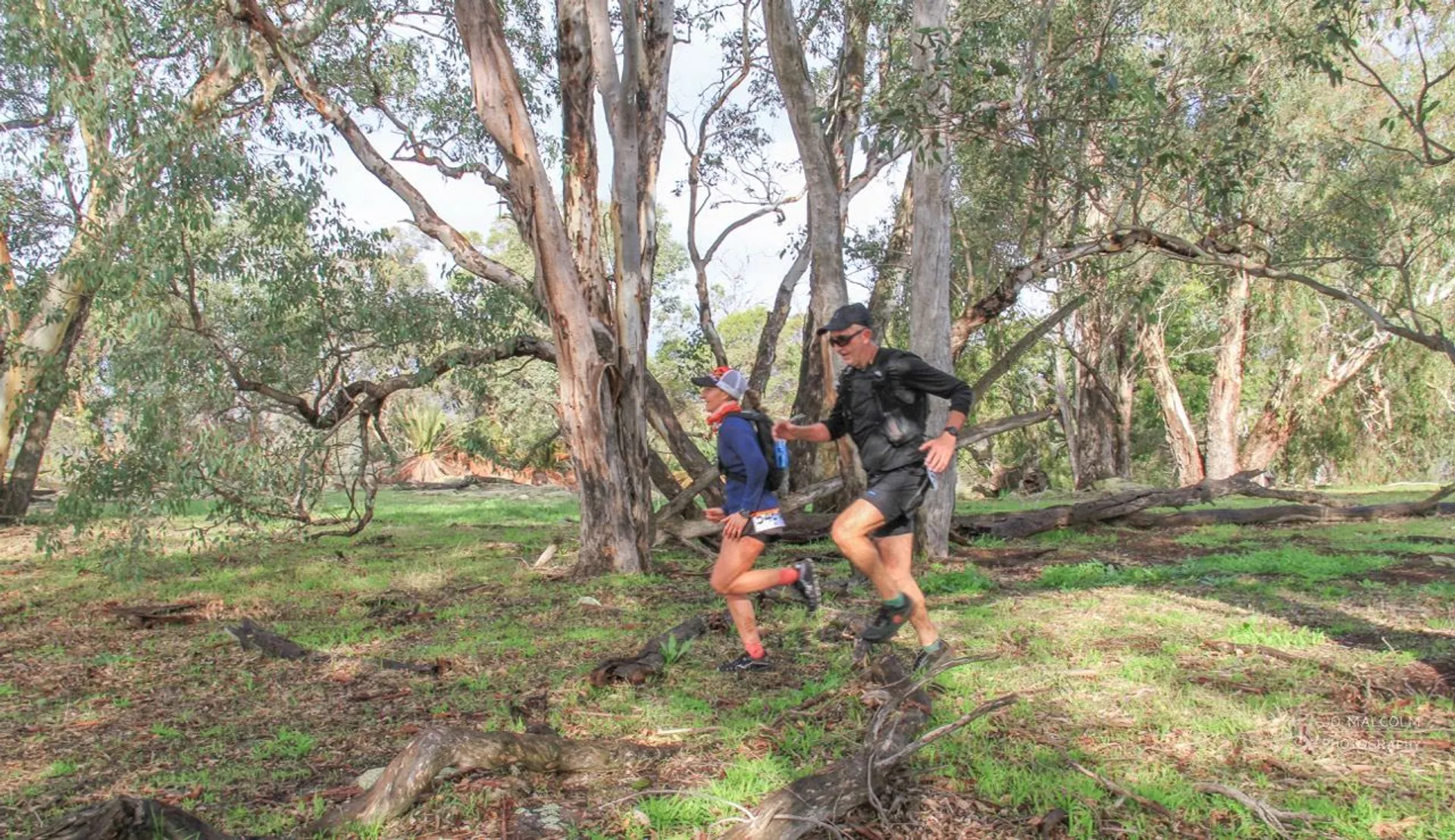 The image shows two people engaged in an outdoor activity in a natural setting, likely