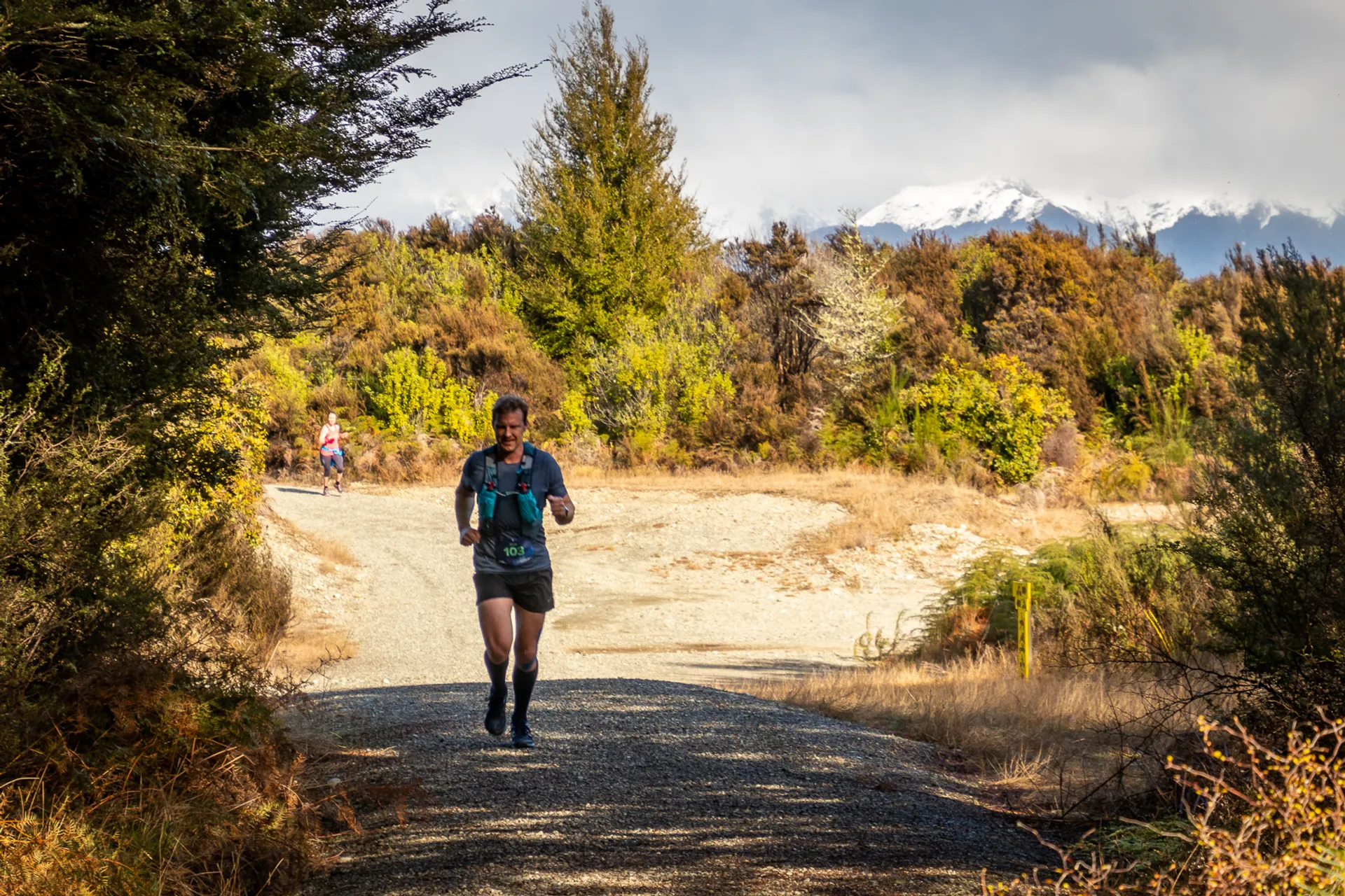 In this image, there is a person running or jogging down a trail or a