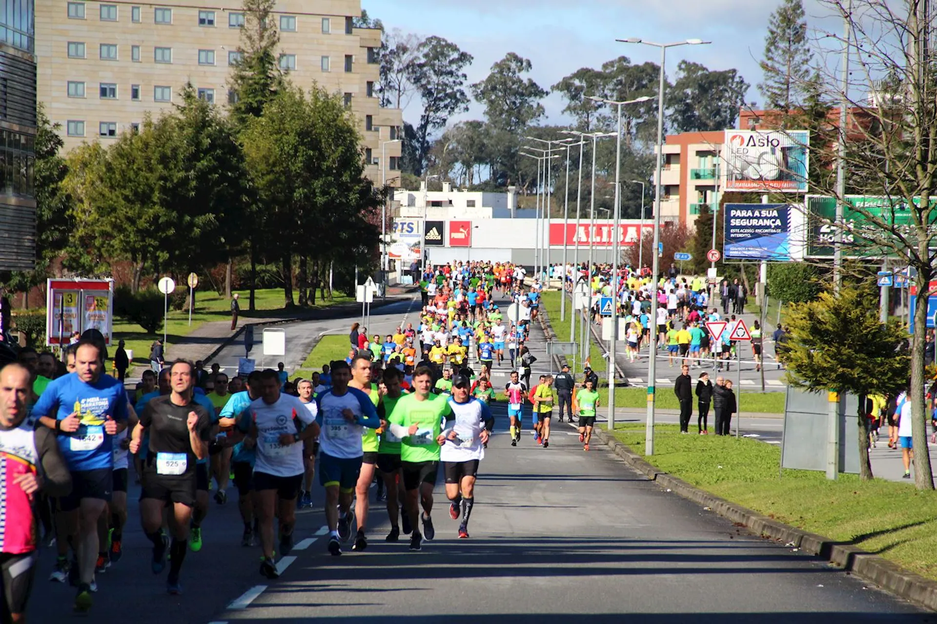 The image shows a large group of people participating in a road running event. The