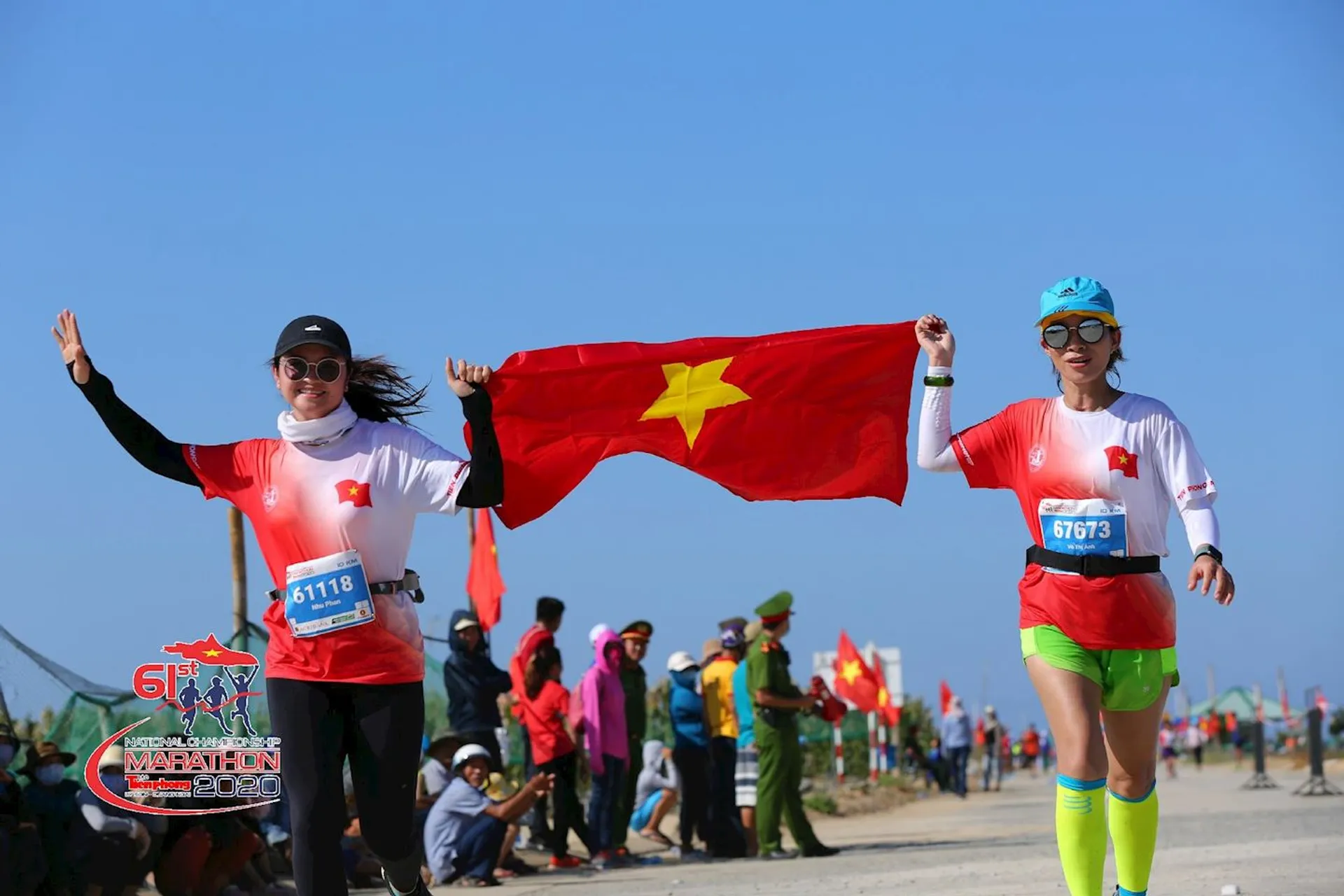 The image shows two individuals participating in a running event. They are holding a flag