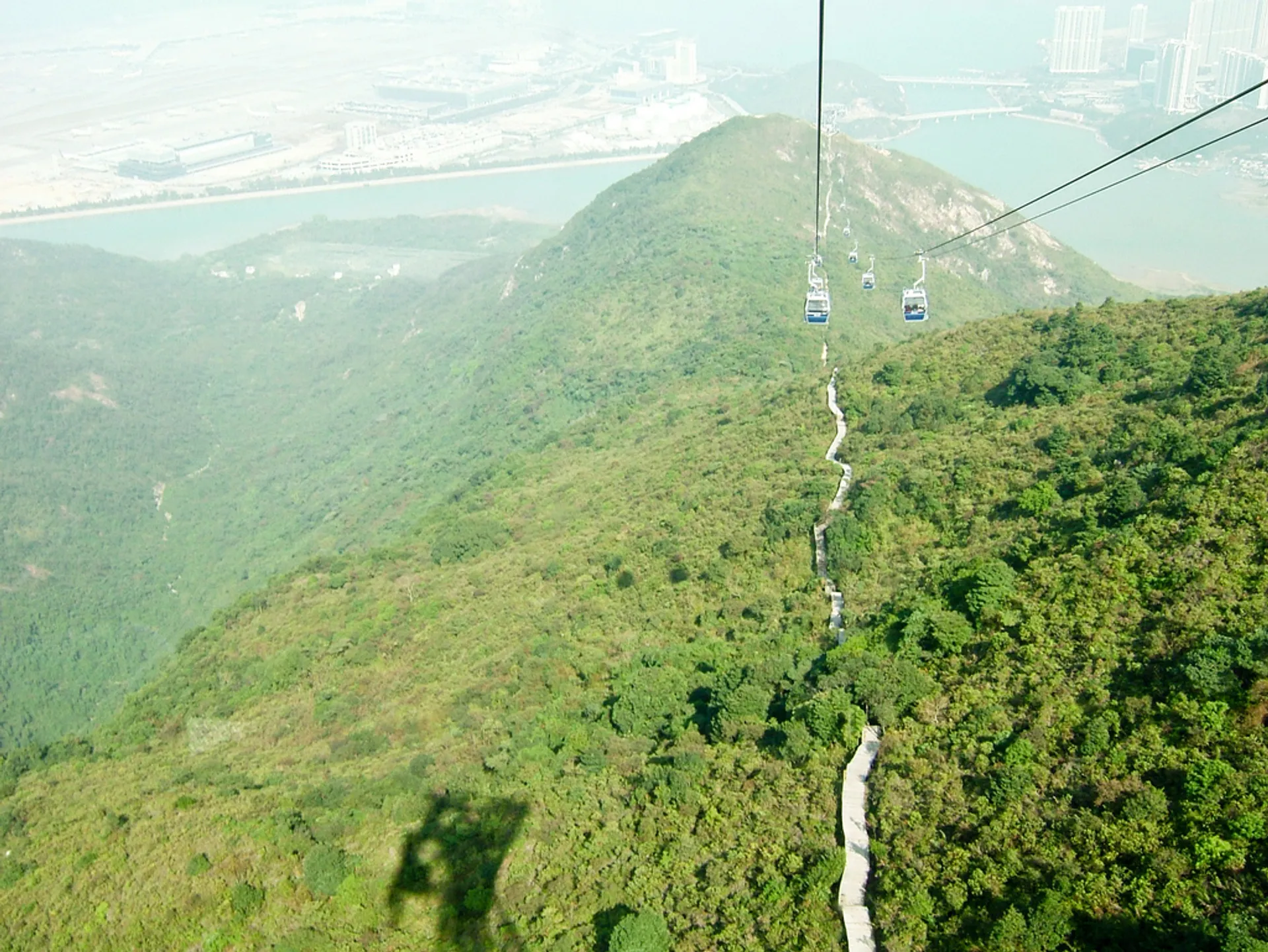 The image depicts a scenic aerial view of a cable car system. Several cable car