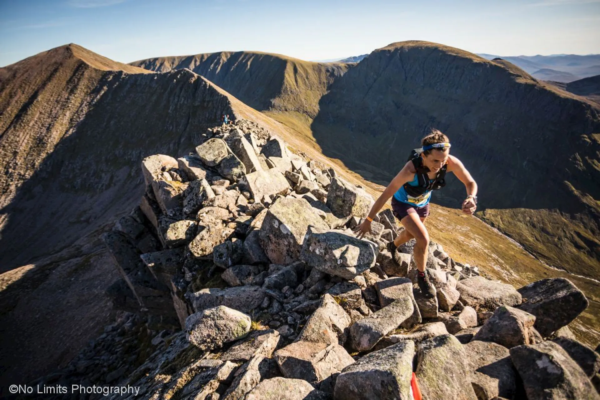 The image depicts an individual engaging in mountain or trail running. The person is wearing