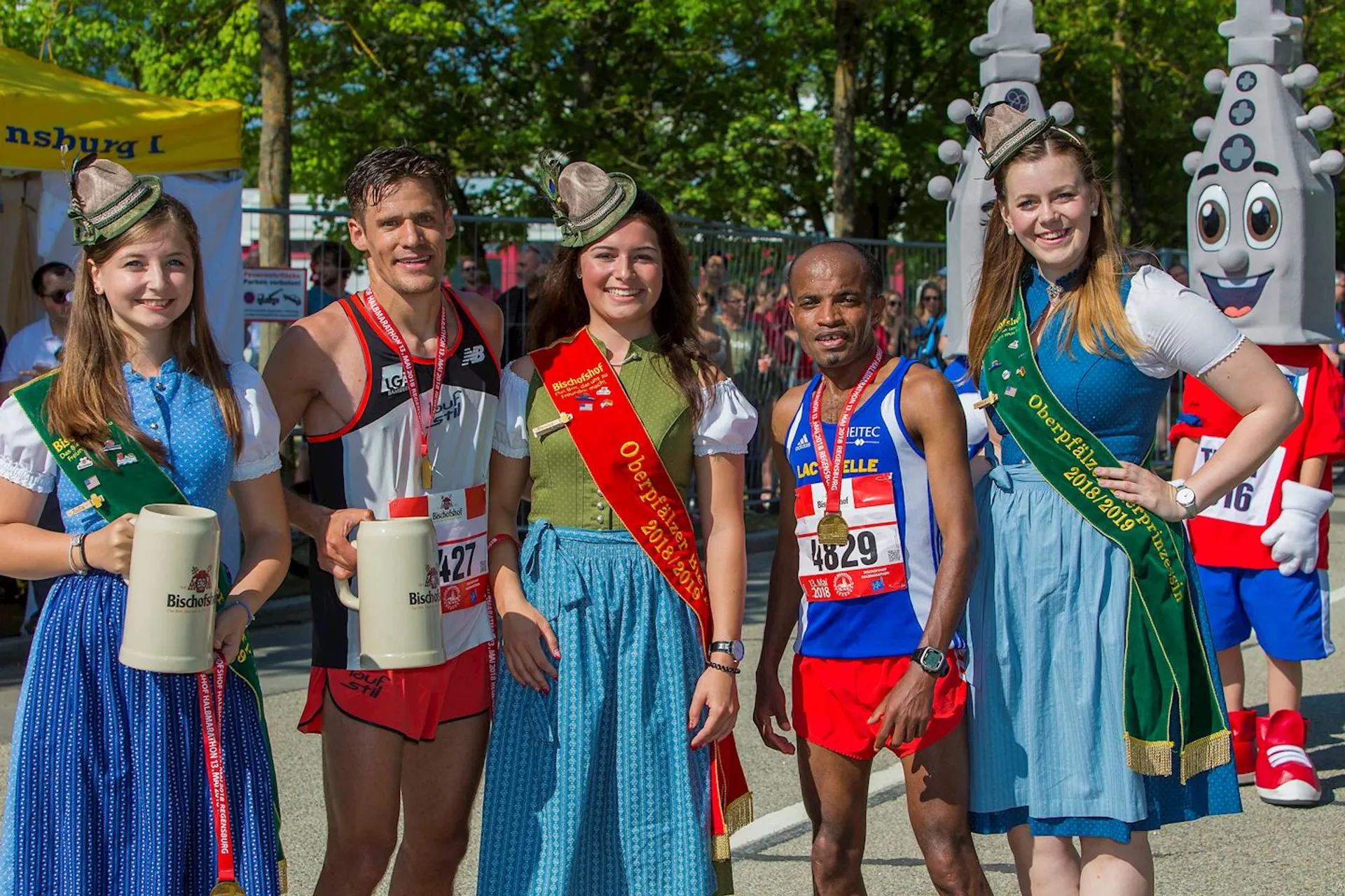 The image shows a group of four people and two mascots at what appears to