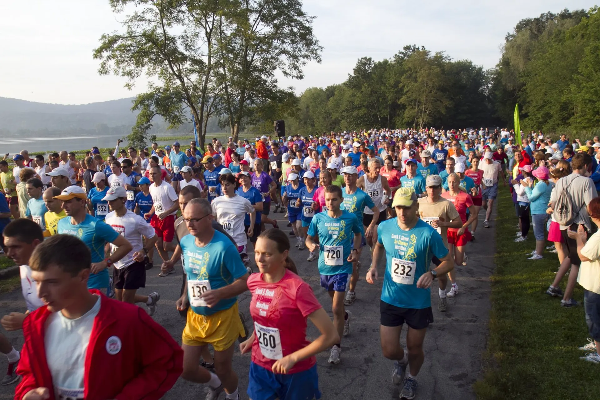The image shows a large group of people participating in a running event. They are