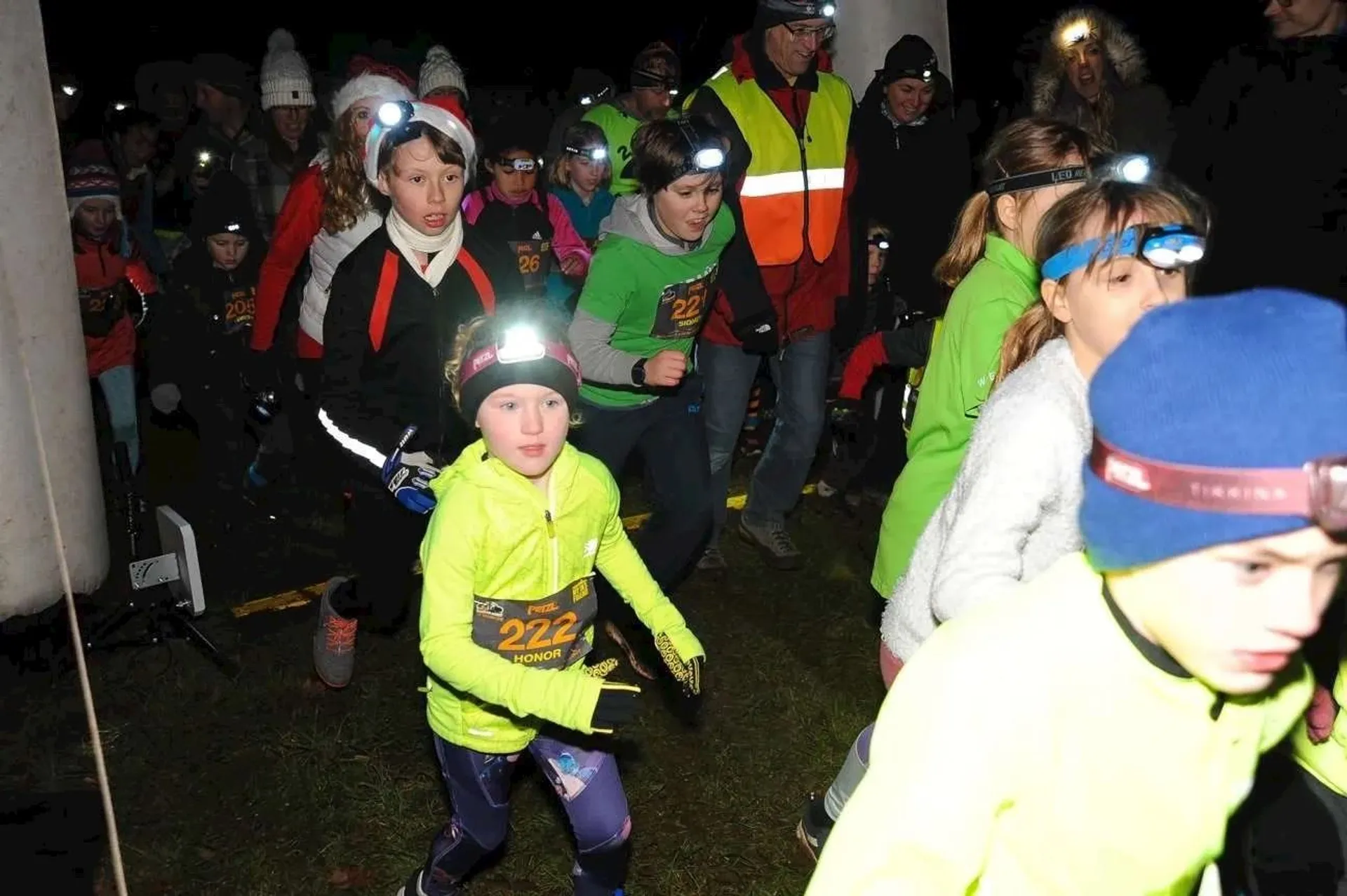 The image depicts a group of people, including children, participating in a nighttime event
