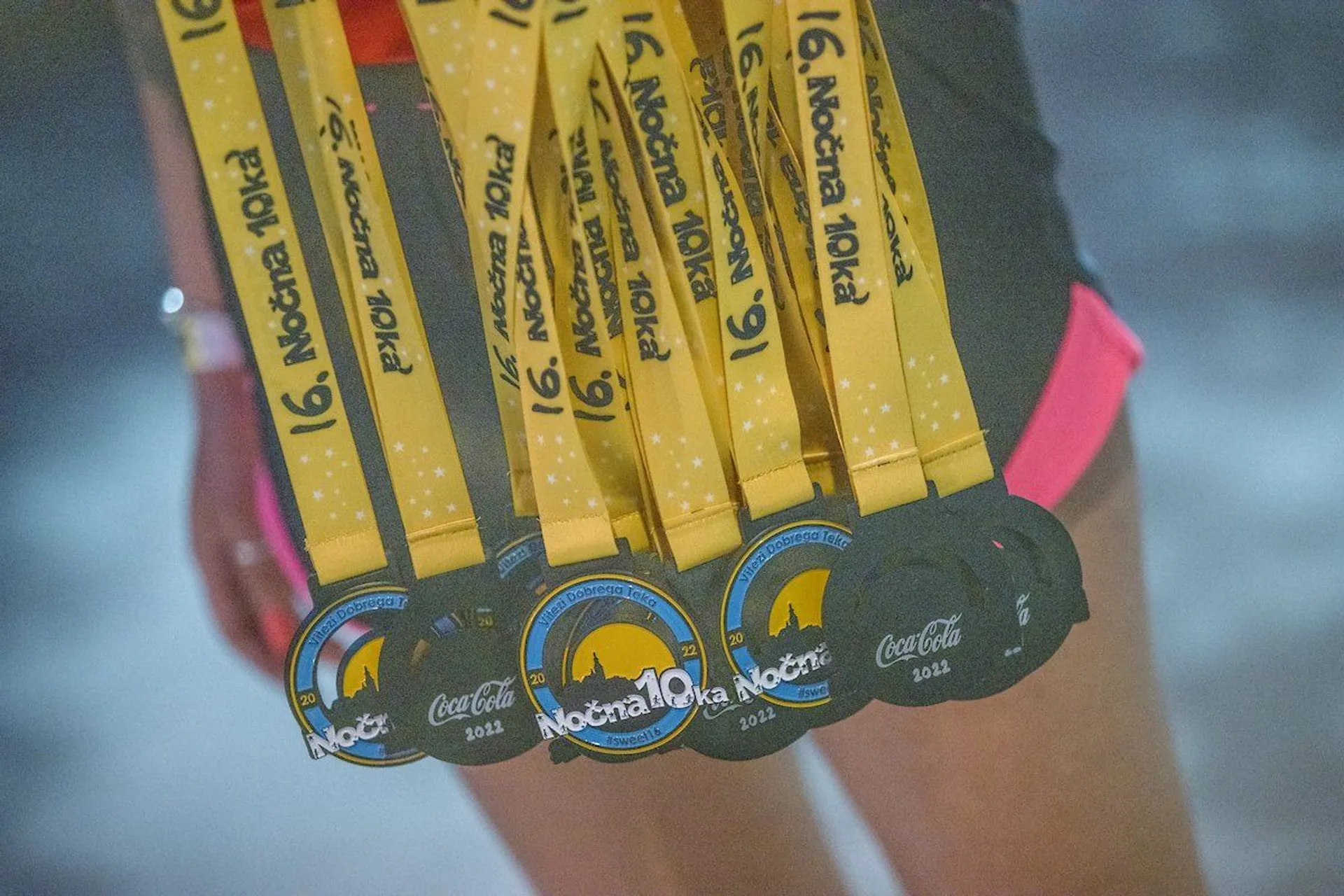 The image shows a collection of medals hanging from a yellow ribbon with text on it