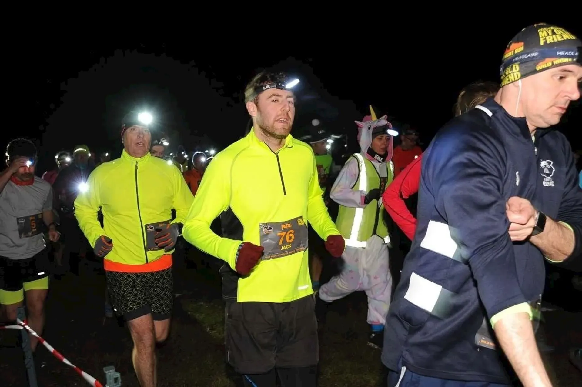 The image shows a group of people participating in a night running event. They are