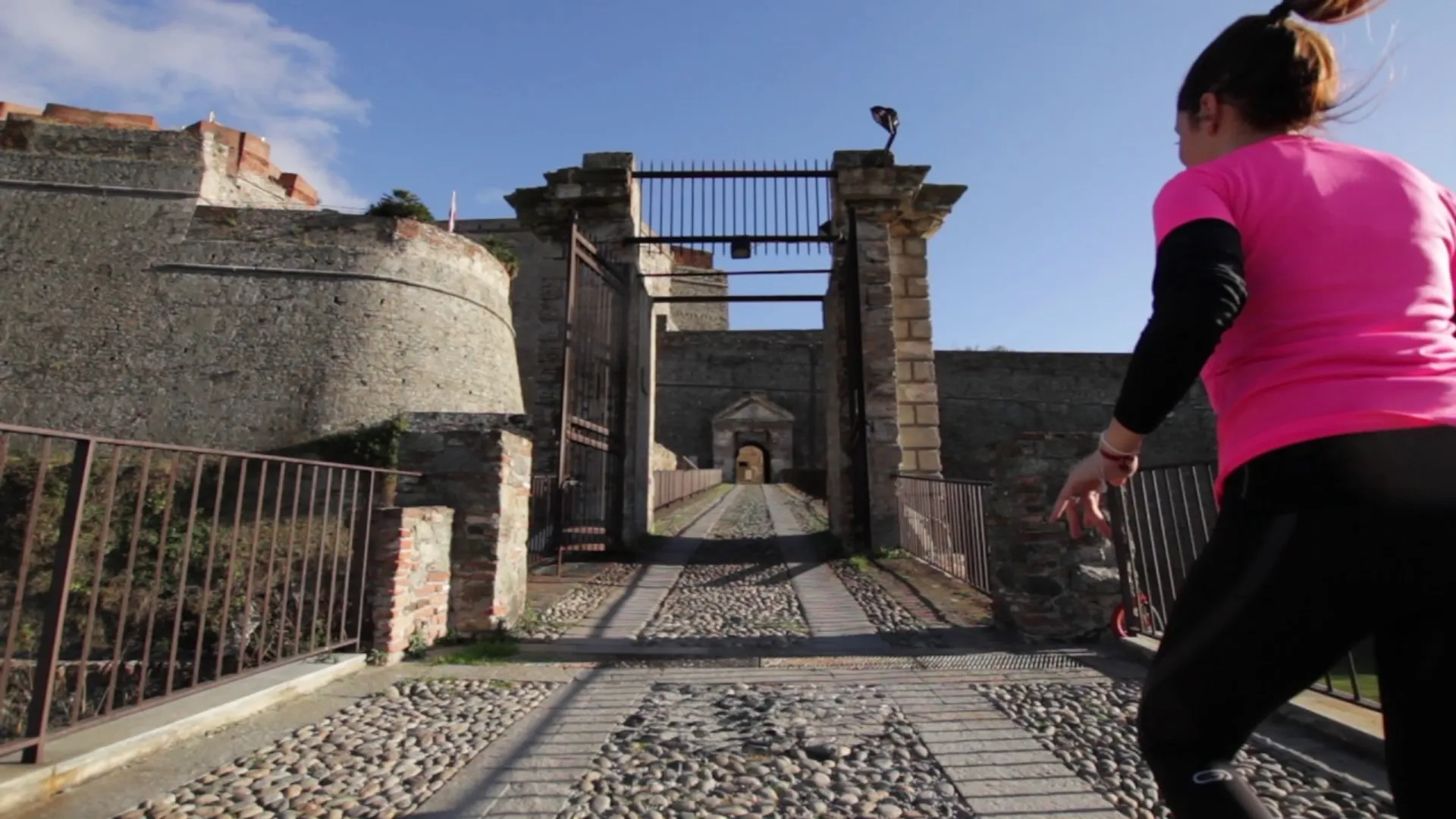 The image shows an outdoor scene where a person wearing a pink top and black pants