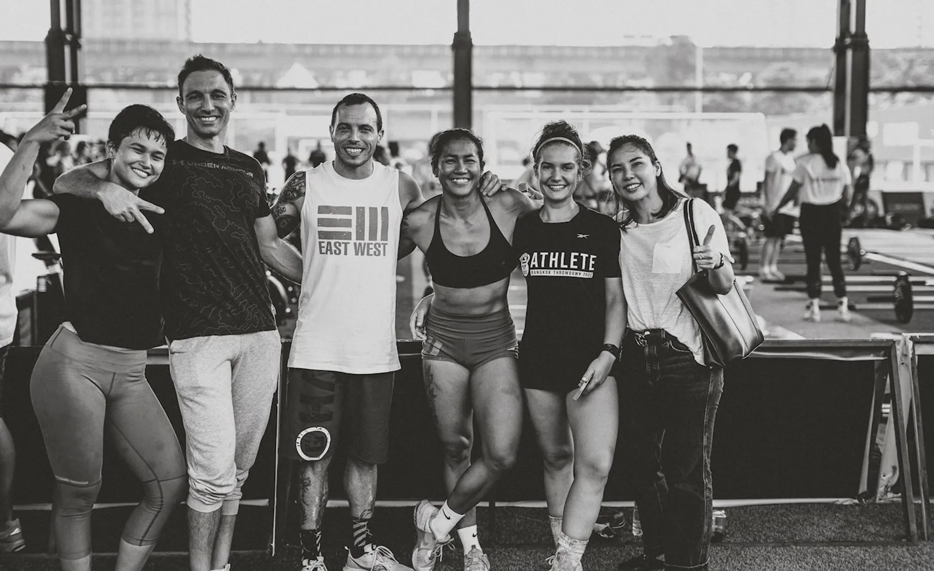 The image shows a group of six happy people posing together for a photo. They