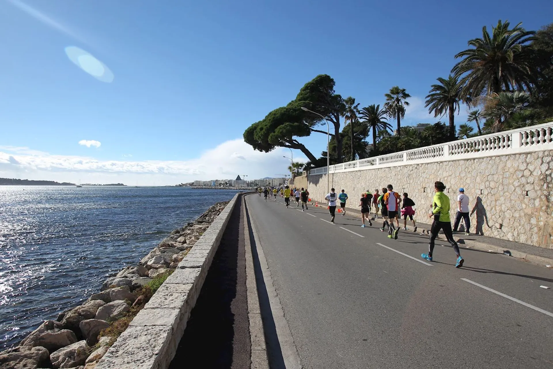 The image shows a group of people running along a coastal road next to a body