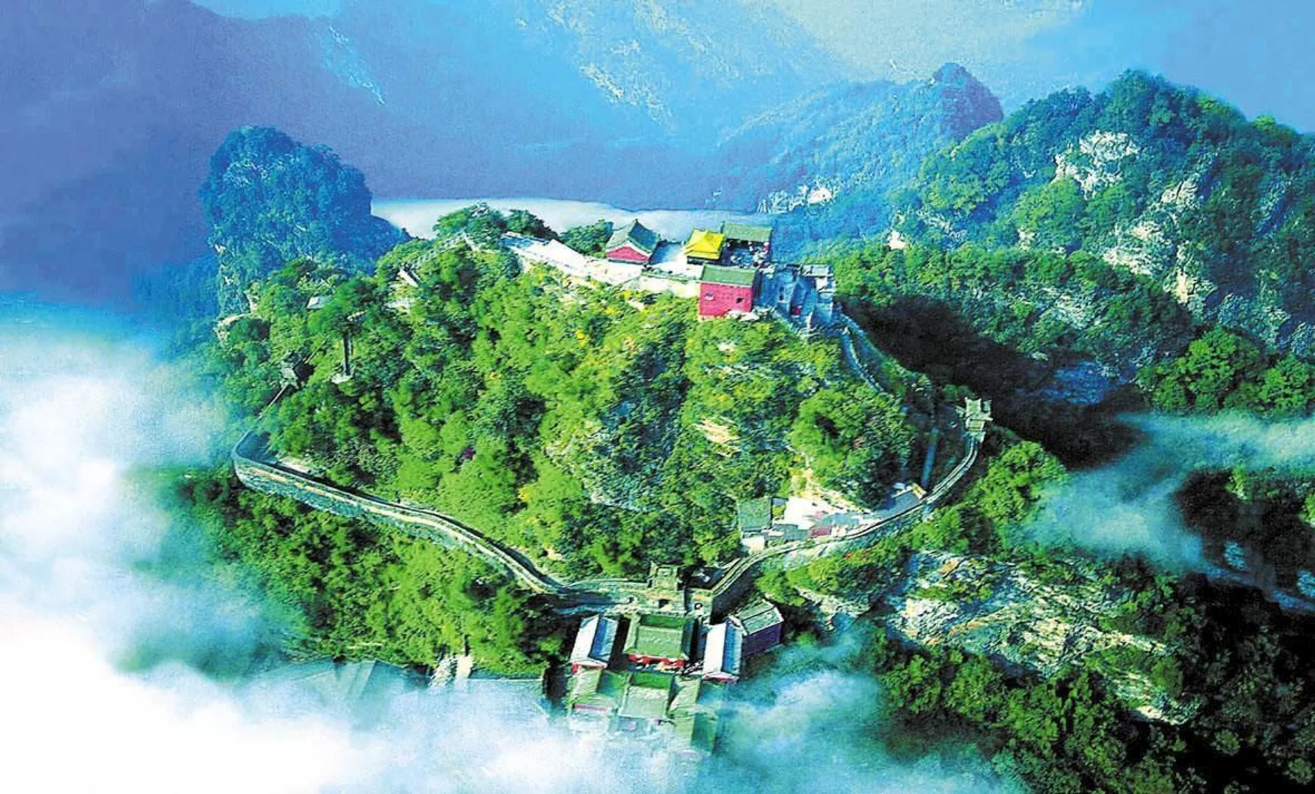 The image depicts a dramatic mountain landscape with a series of buildings that appear to be