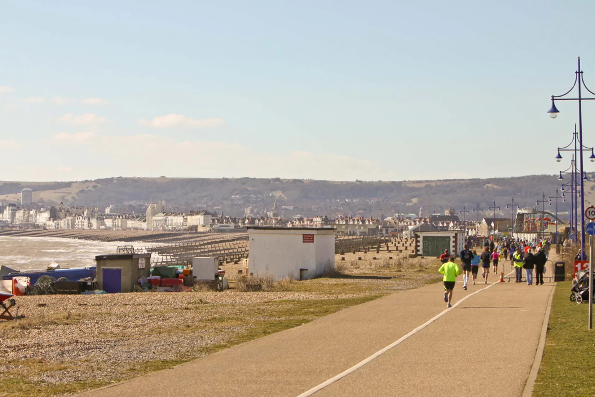The image shows a seaside promenade with people engaged in various activities such as walking