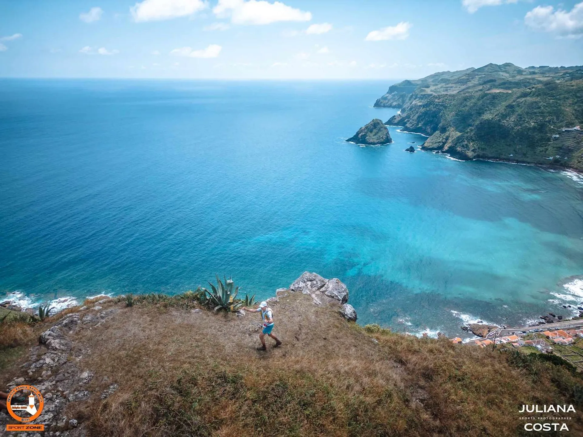 The image shows a breathtaking coastal landscape. In the foreground, there's a person