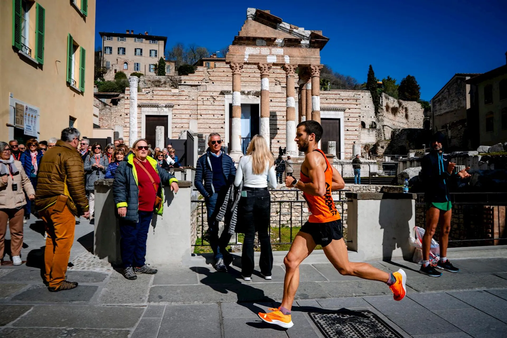 The image captures a scene with a male runner in athletic gear sprinting past a