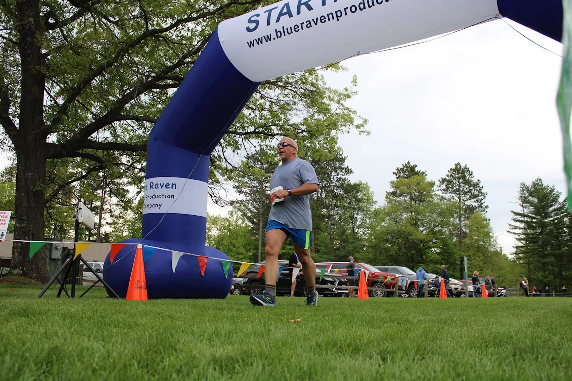 The image shows an outdoor event where a person is seen passing under an inflatable arch
