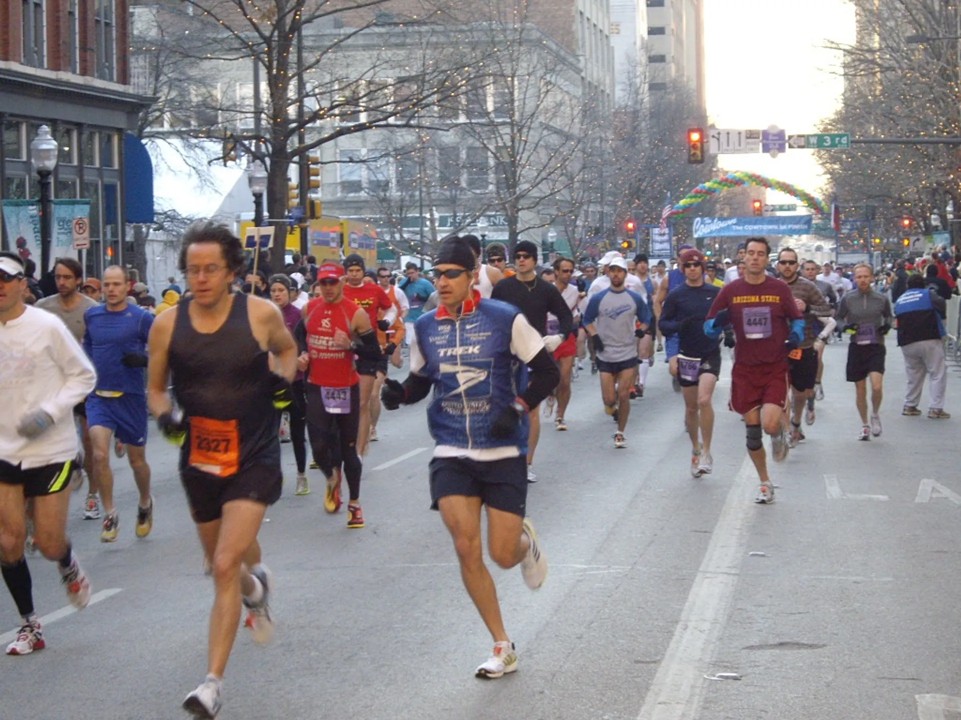 The image depicts a group of people participating in a road race, likely a marathon