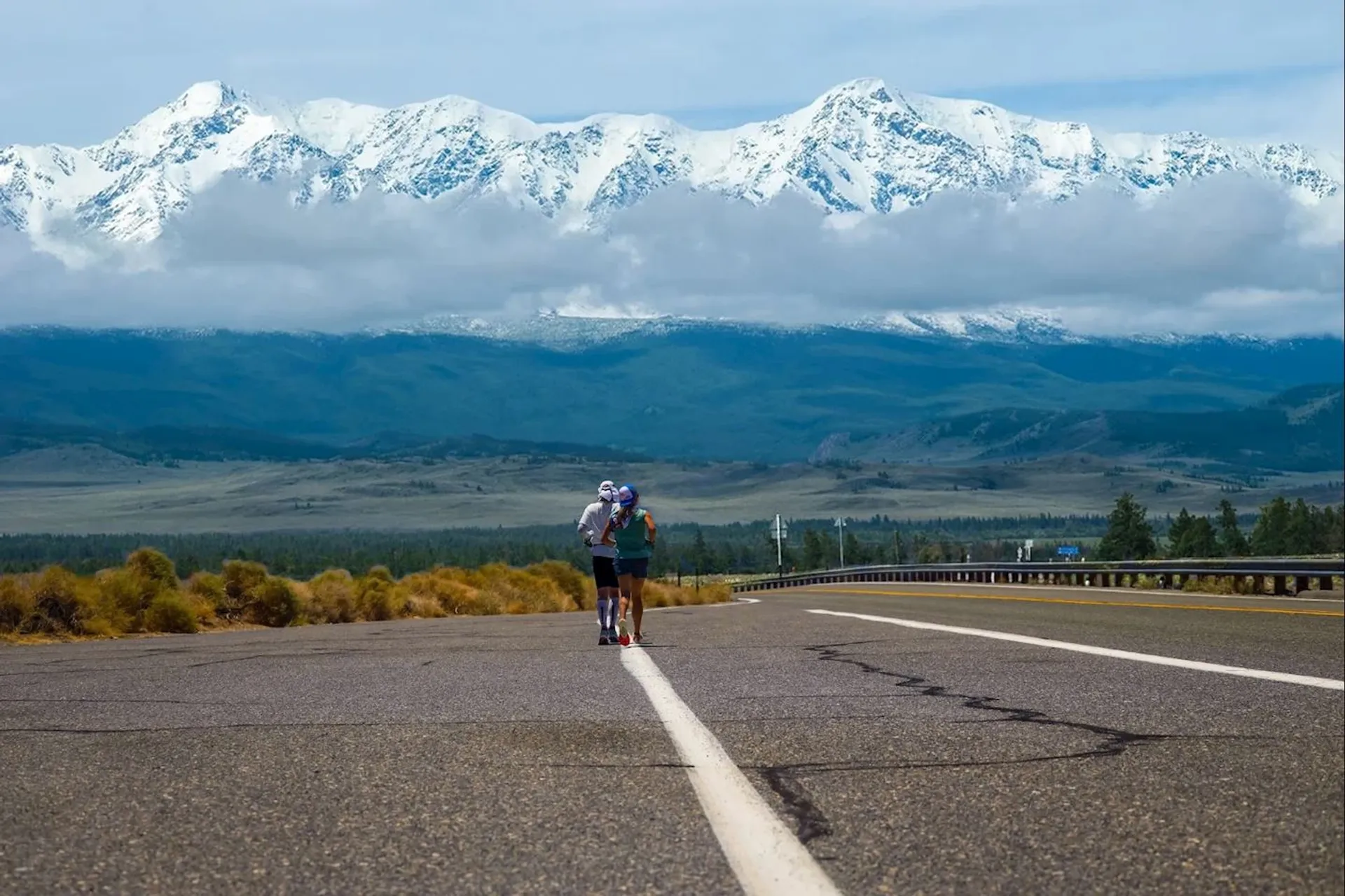 The image shows a scenic road with a person cycling. The cyclist is wearing a