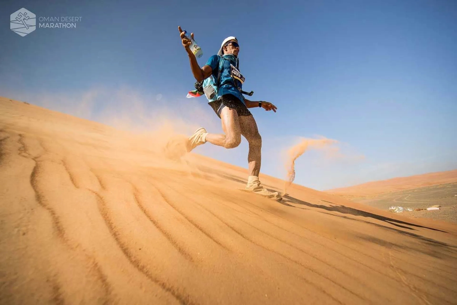 The image shows a runner in action during a desert marathon. The participant is dressed