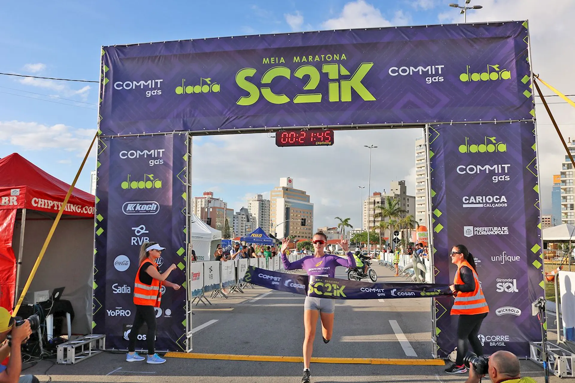 The image shows a person just crossing the finish line of a half marathon race,