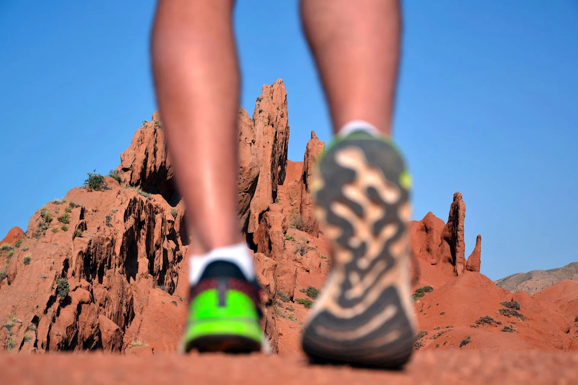 The image shows a person's lower legs and running shoes, with a backdrop of