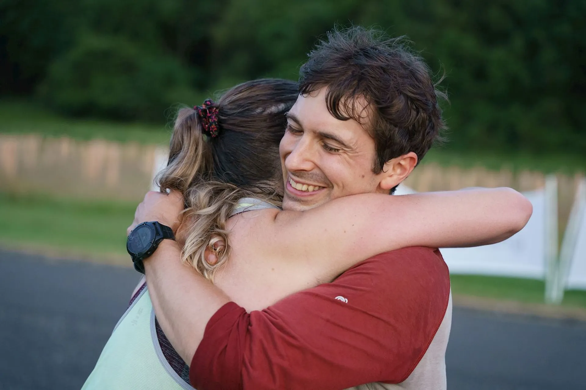 The image shows two people embracing in a hug. The person on the right appears