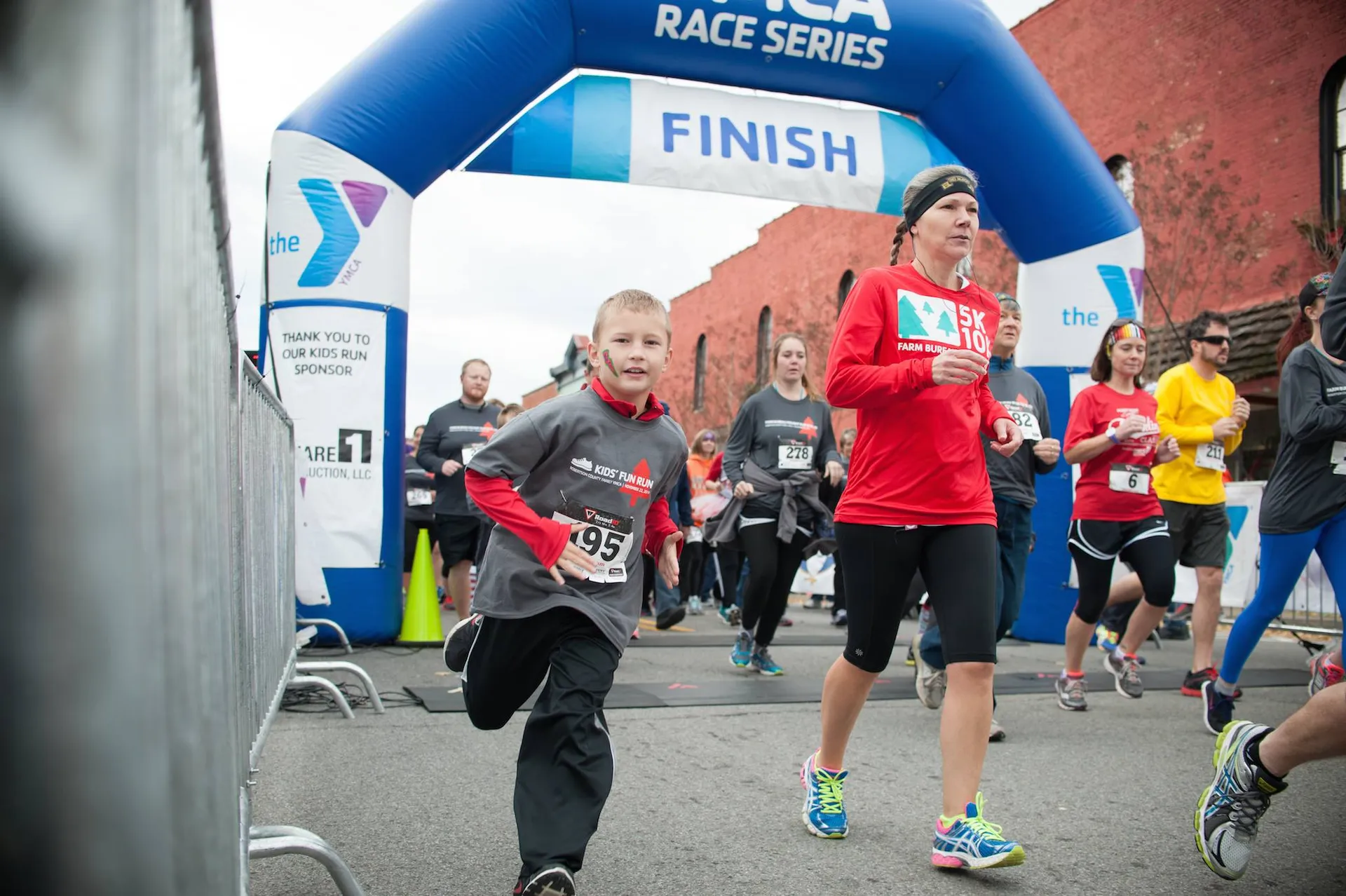 The image shows an outdoor event where participants are crossing the finish line of a race
