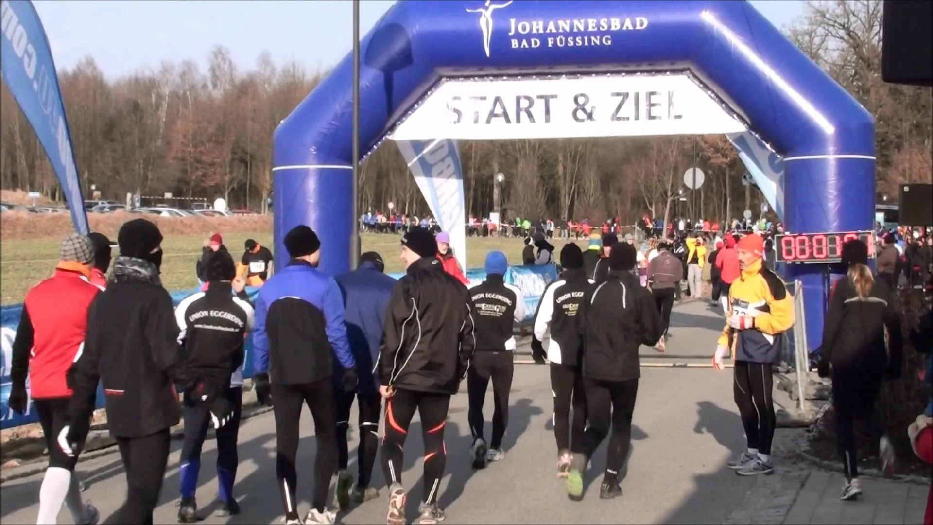 The image depicts a group of runners at the start of a race. They are