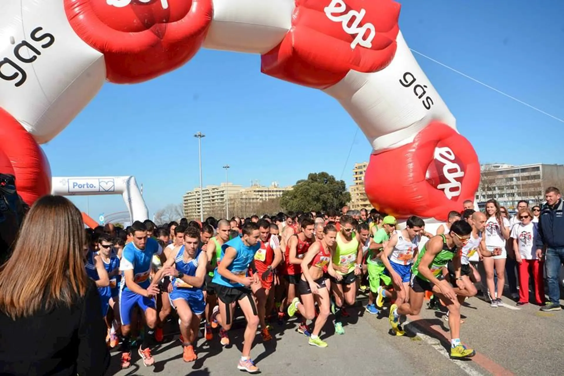 The image shows a group of runners at the start line of a race. They