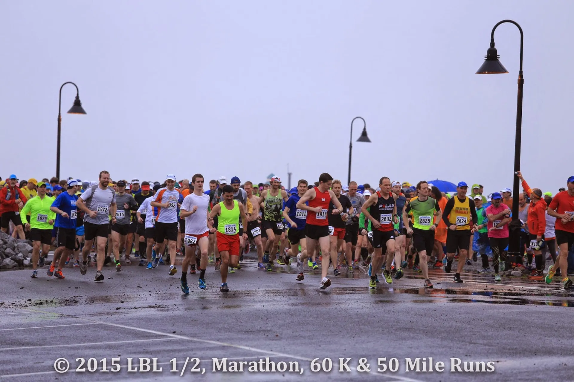 The image features a road race event with numerous participants at the starting moment or shortly