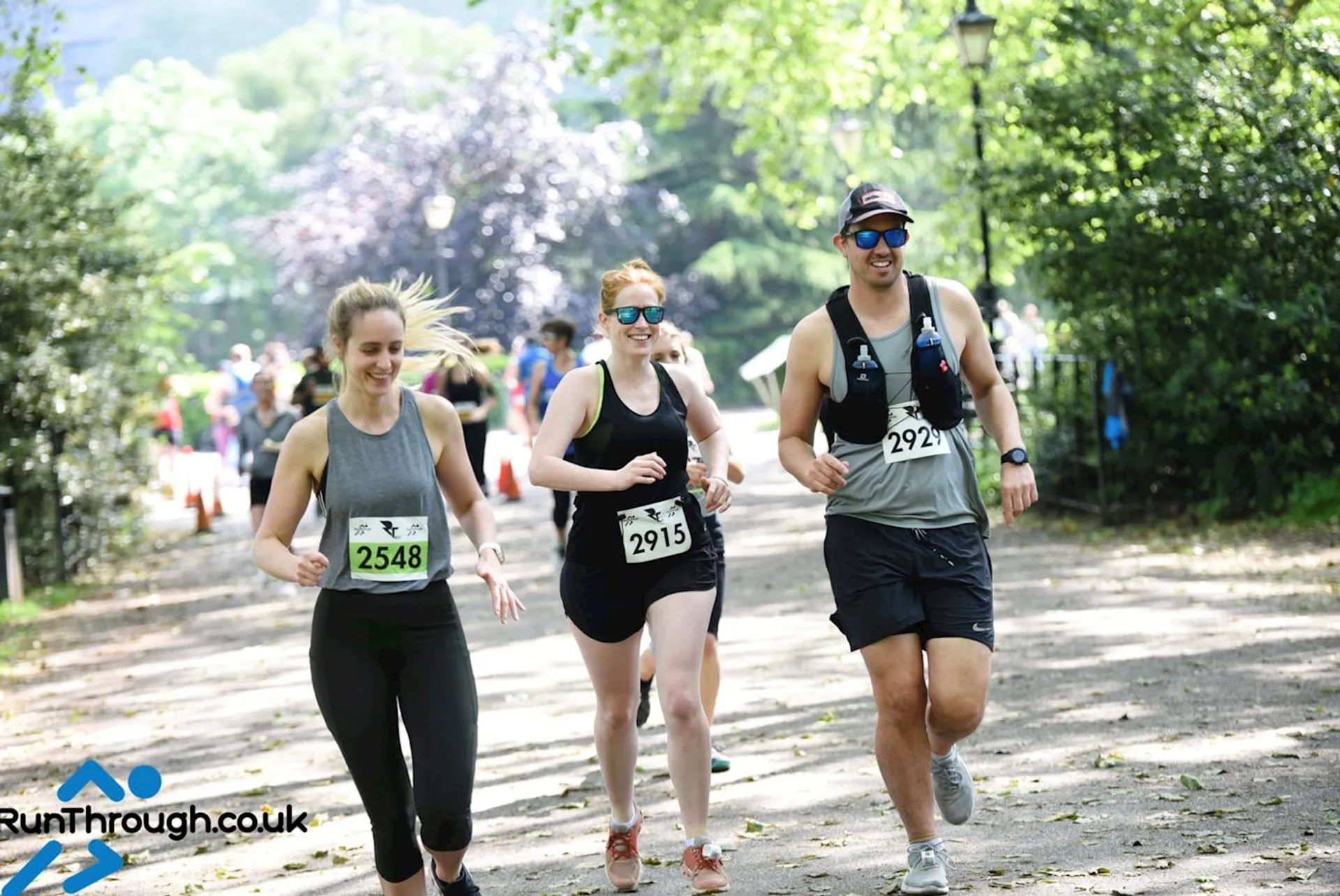 The image depicts three people engaged in a running event, as indicated by their bib