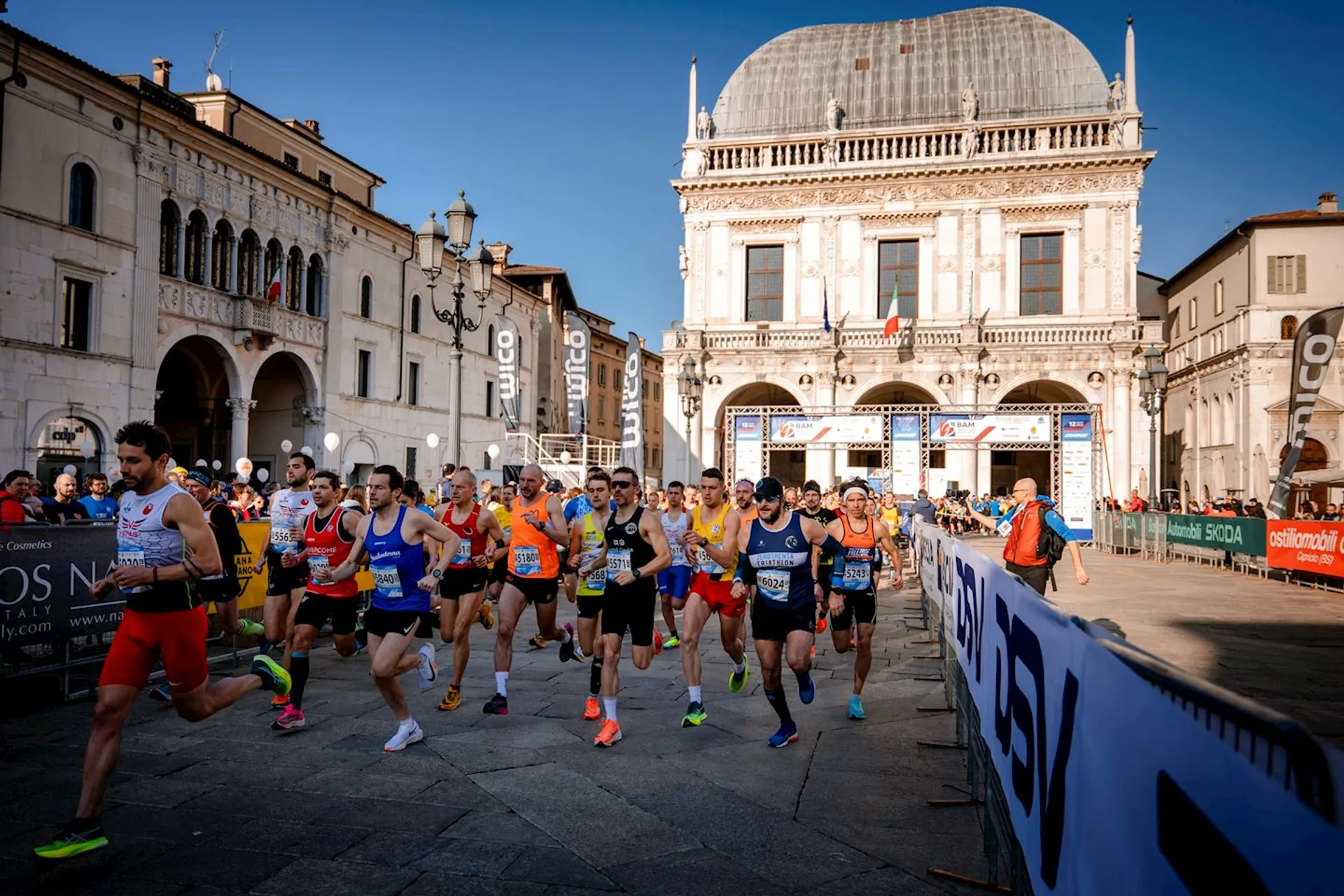This image depicts a group of runners at the start of a road race. They