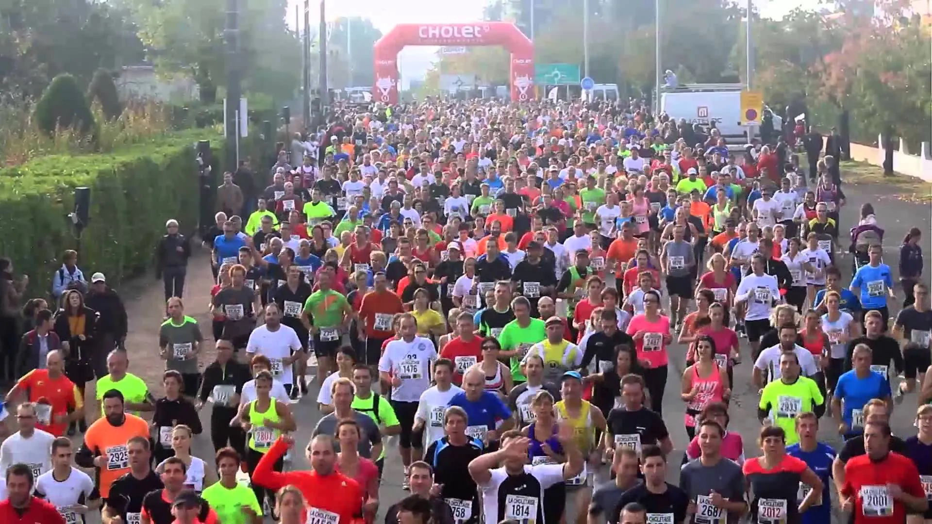 The image shows a large group of people participating in a running event. In the