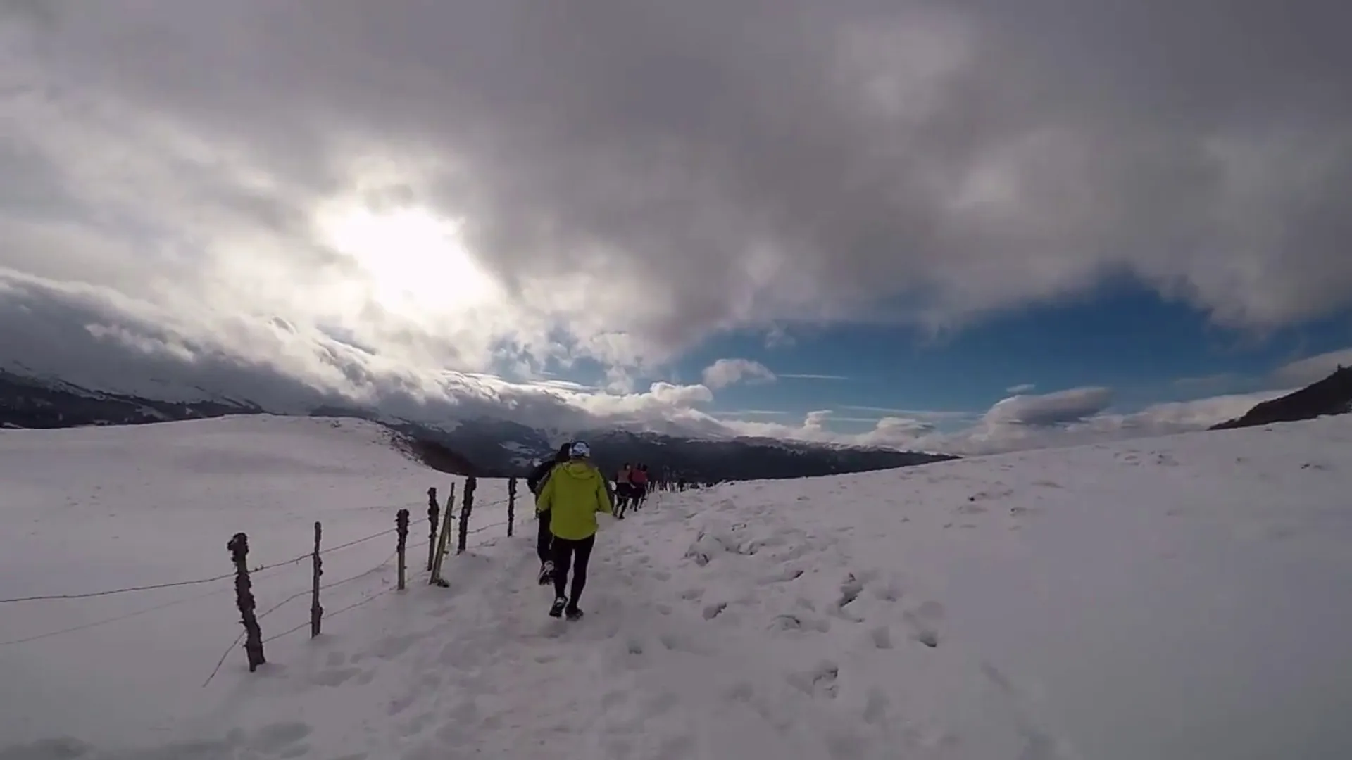 The image shows a group of people engaged in a winter activity, likely hiking or