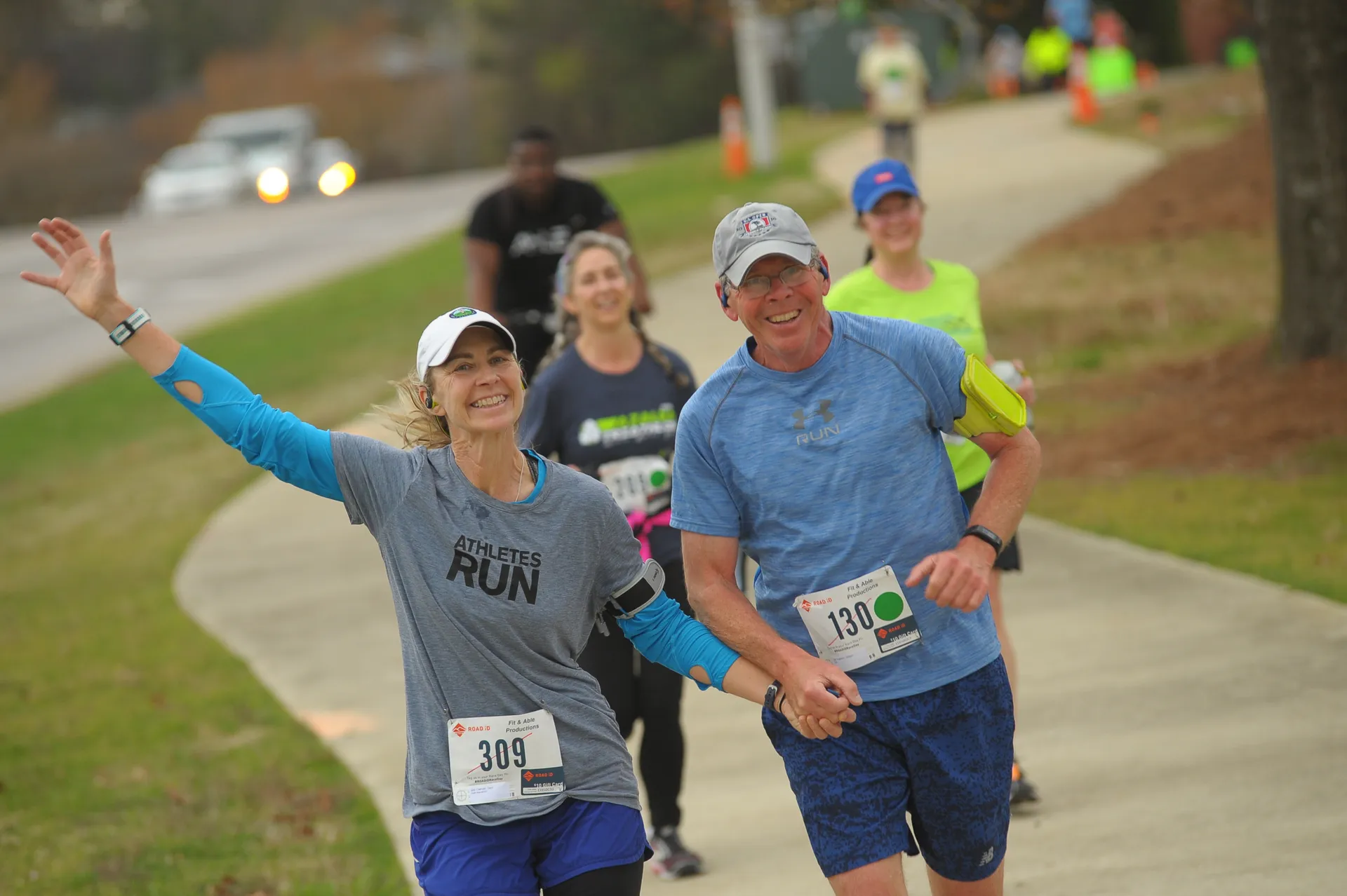 The image shows a group of people participating in a road race or fun run.