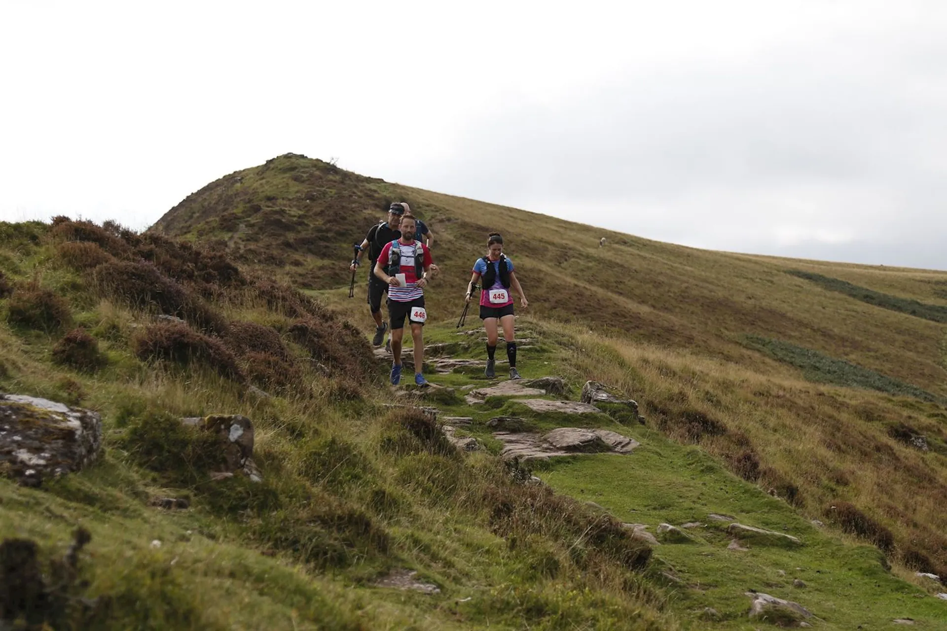 The image shows three individuals participating in what appears to be a trail run or a