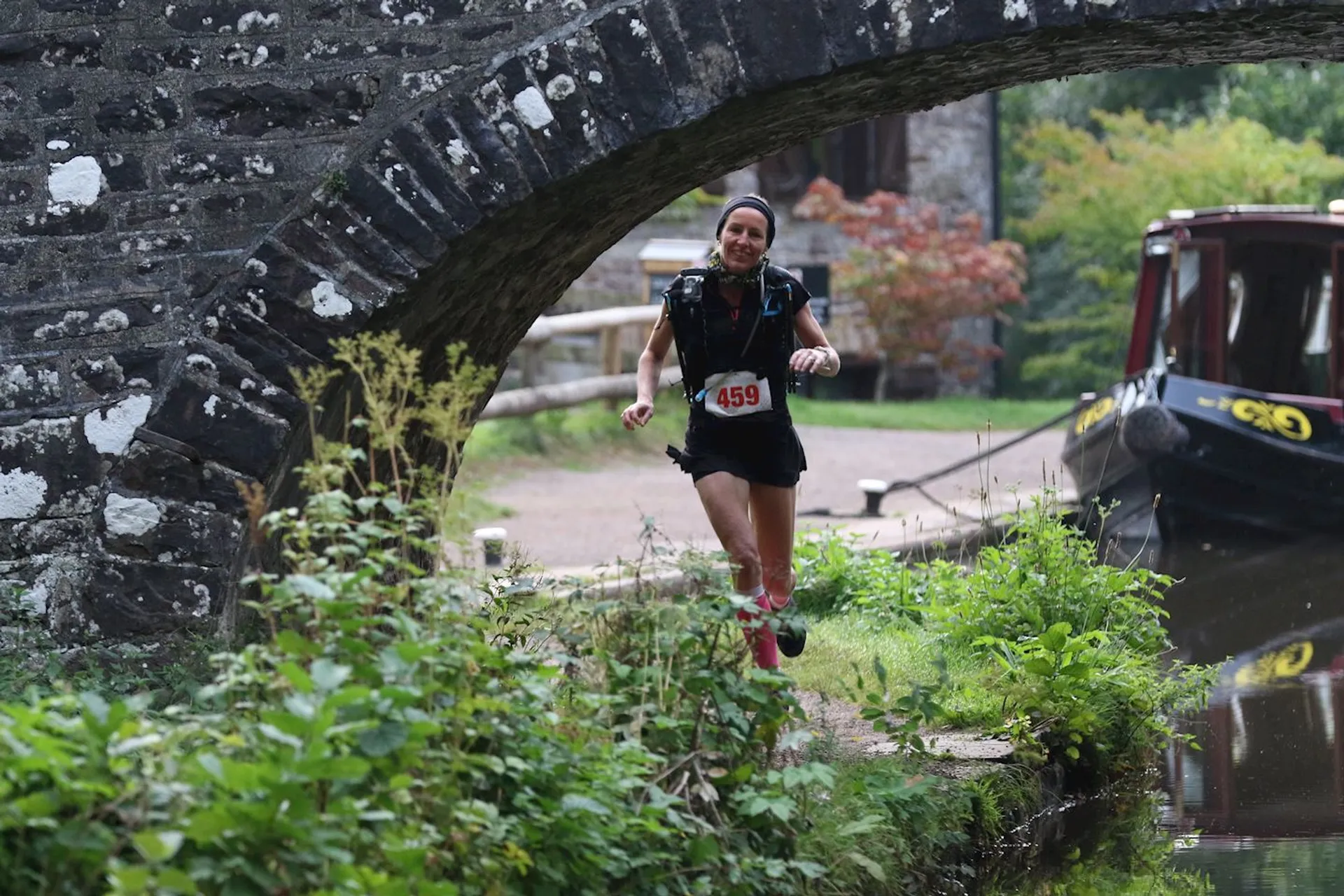 The image depicts a person running toward the camera through a picturesque setting. The runner