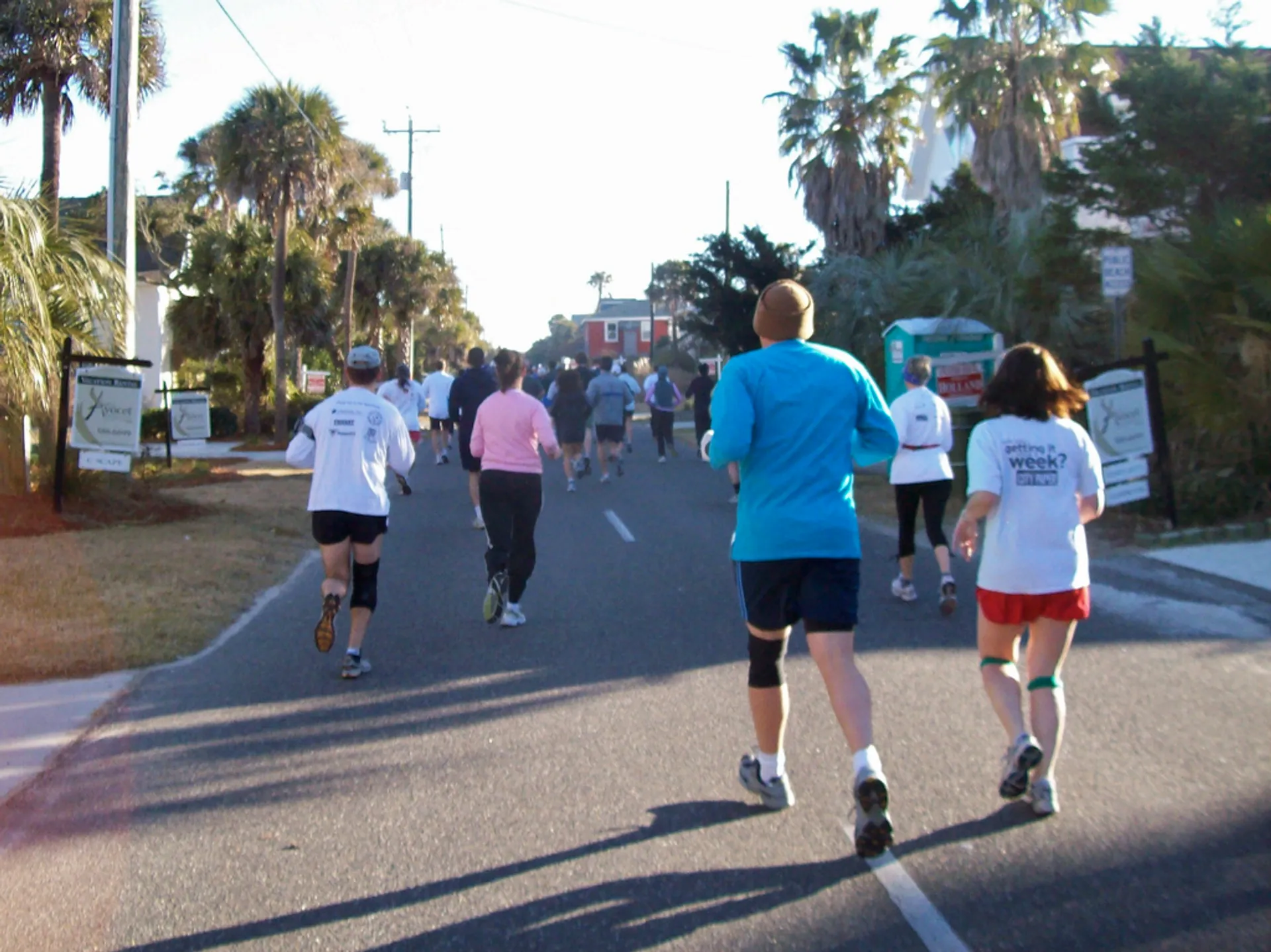 The image shows a group of people participating in a running event on a road.