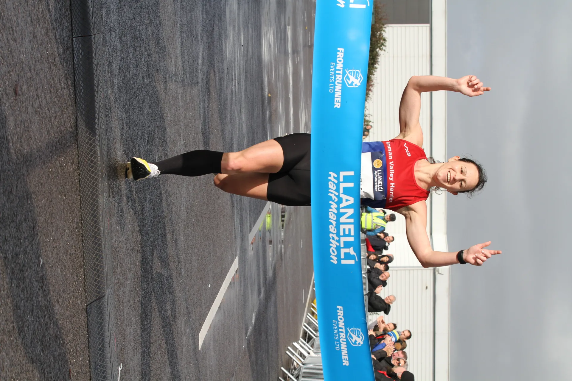 In the image, there is a woman who appears to be crossing the finish line