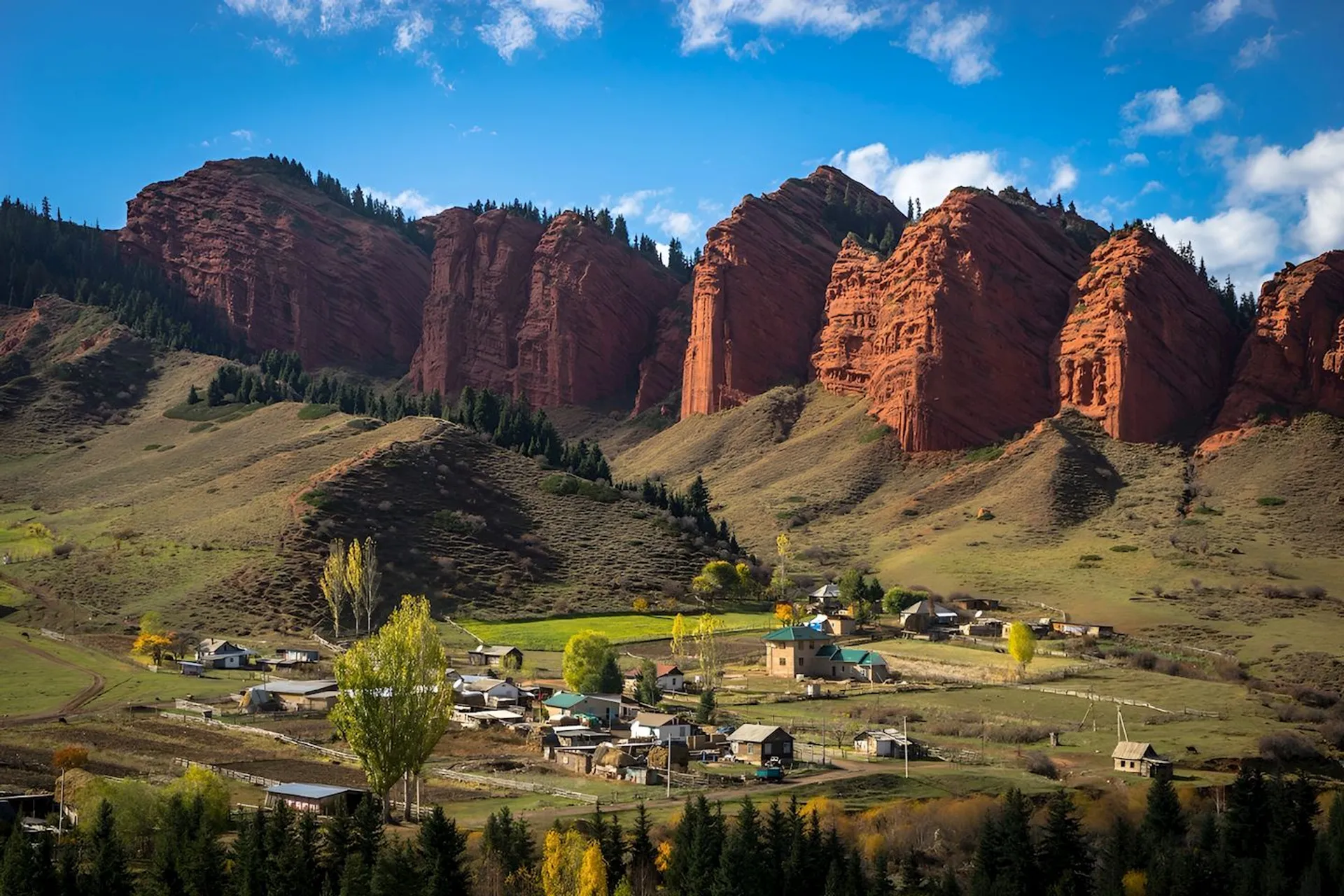 This image depicts a picturesque rural landscape. In the foreground is a small village with