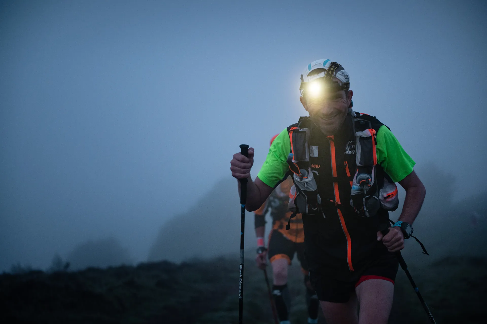 The image depicts a person engaged in what appears to be a trail run or ultr