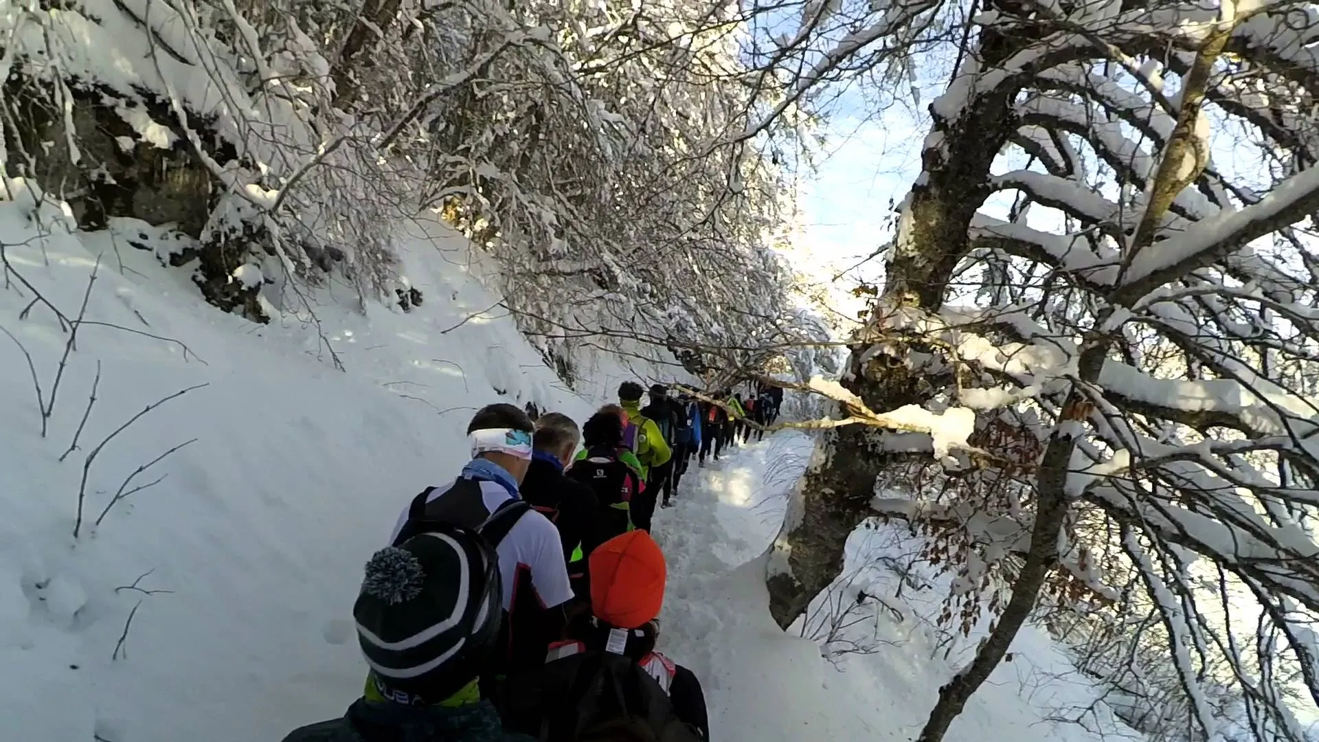 The image shows a group of people hiking through a snowy landscape. They are on