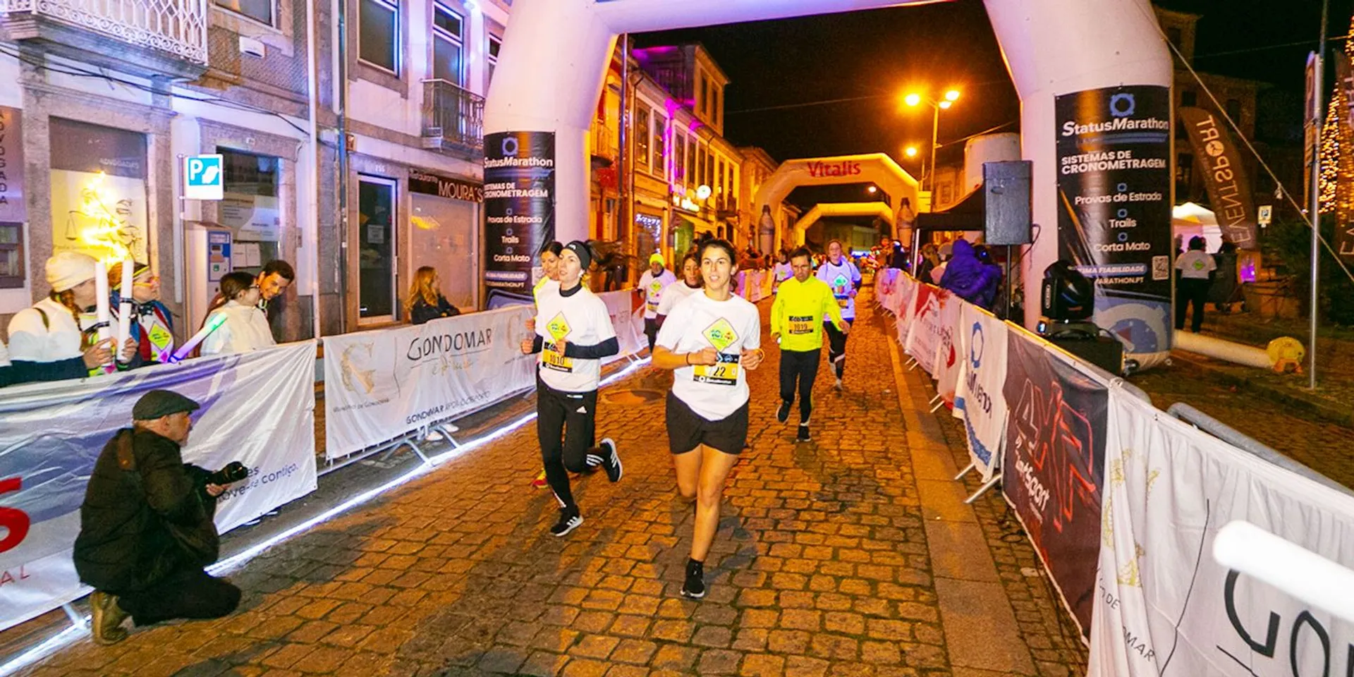 The image shows an evening or nighttime outdoor scene of a running event, likely a