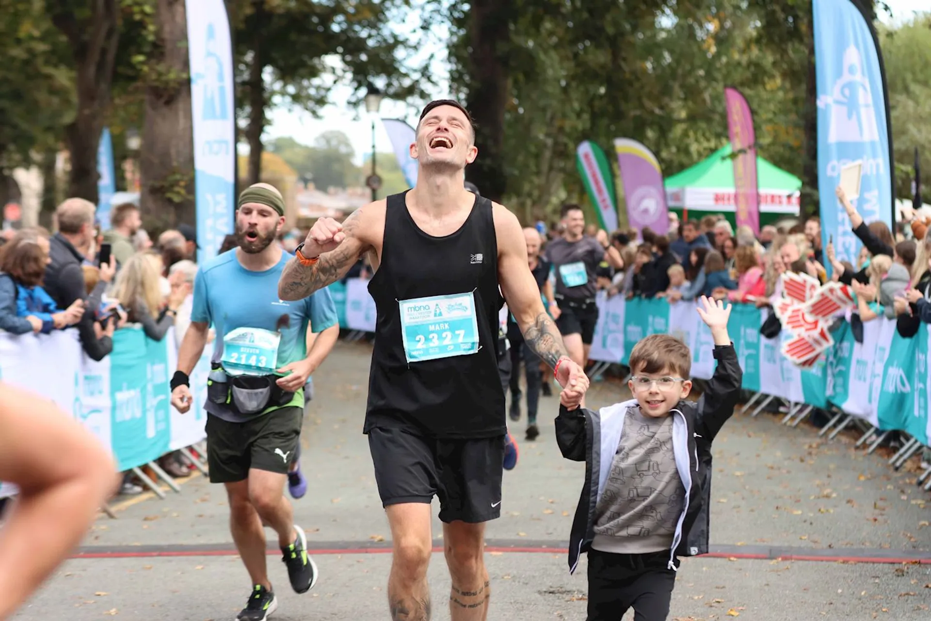 The image shows a joyful moment at a running event. There is a man in
