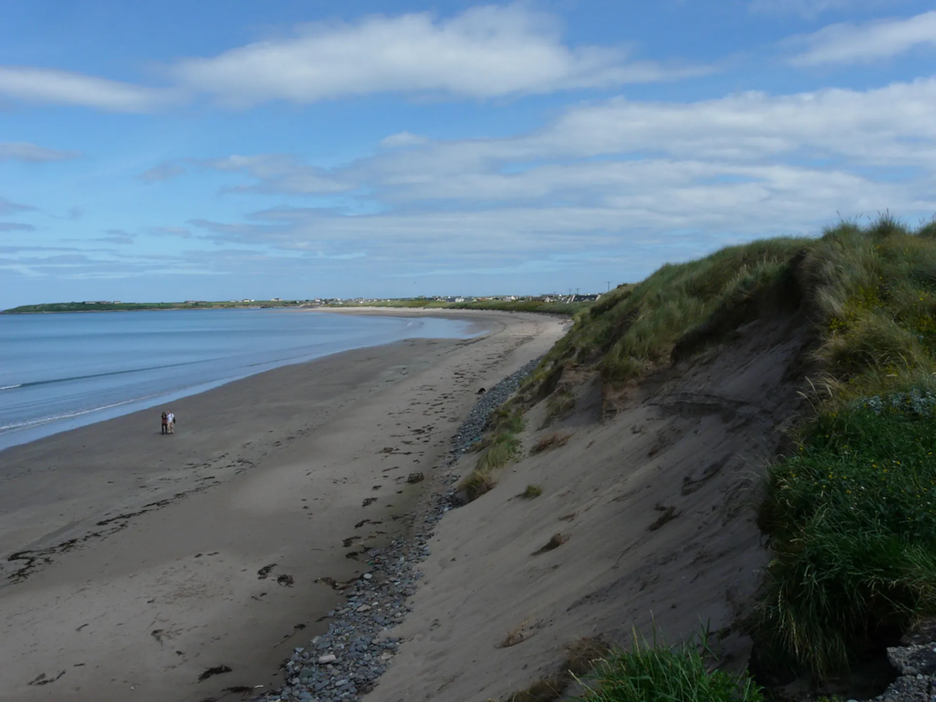 This image features a tranquil beach scene with gentle waves lapping onto a sandy shore