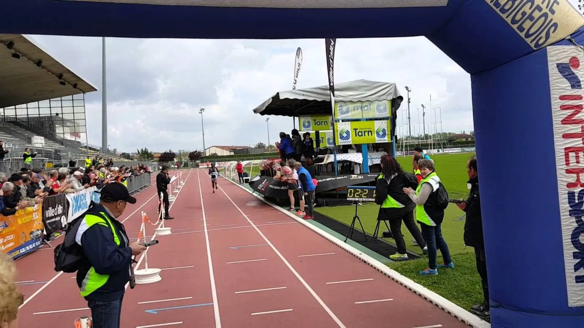 The image shows an outdoor event at a stadium, likely a running or athletic event