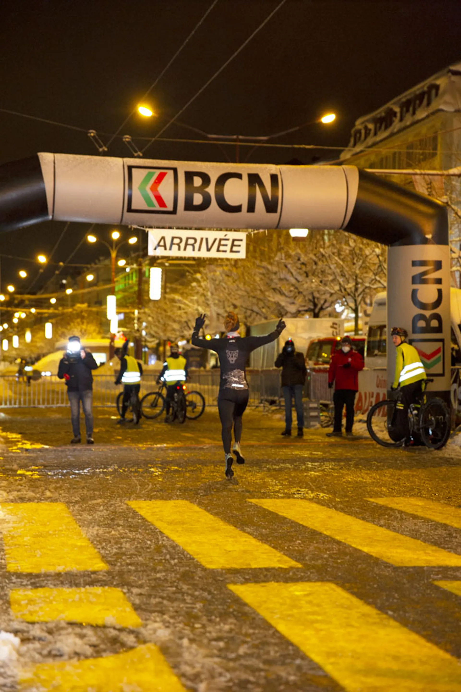 This image captures a runner with arms raised in a victory pose as they cross the